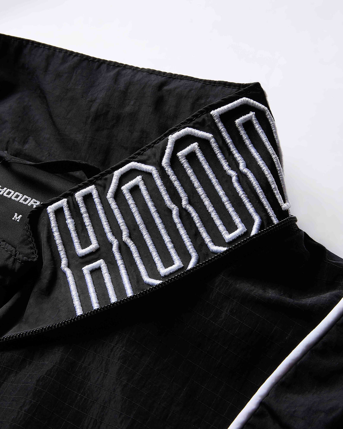 Black jacket with white embroidered text on a white background