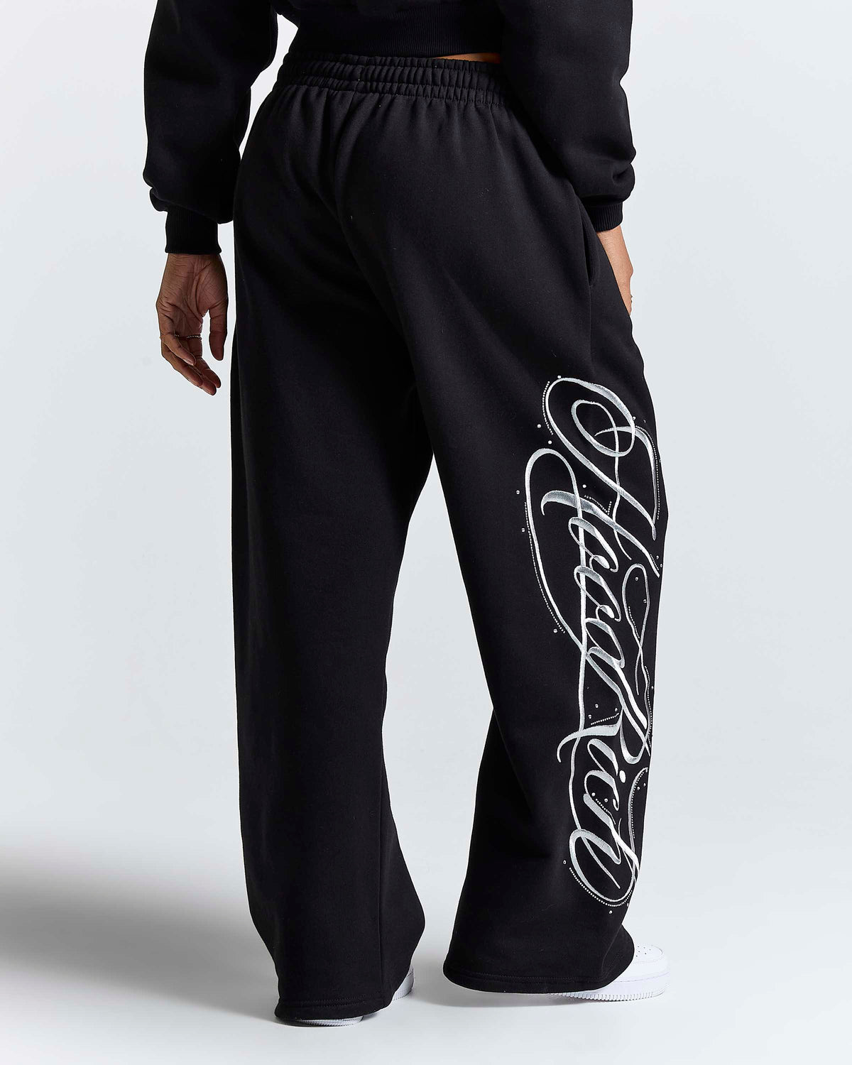 Displays a model wearing the Black 'Hoodrich' branded women's Solace Full Tracksuit