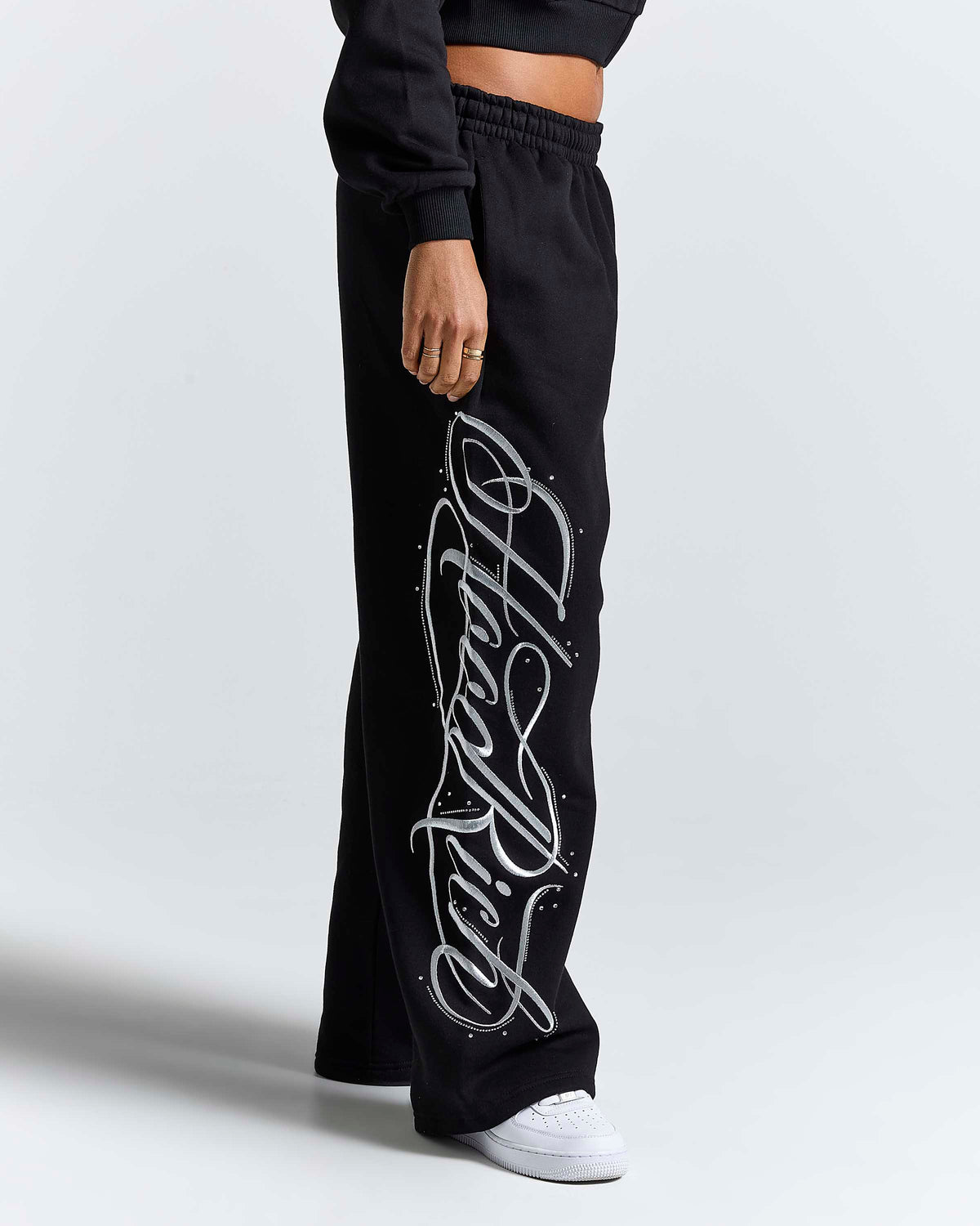 Displays a model wearing the Black 'Hoodrich' branded women's Solace Full Tracksuit