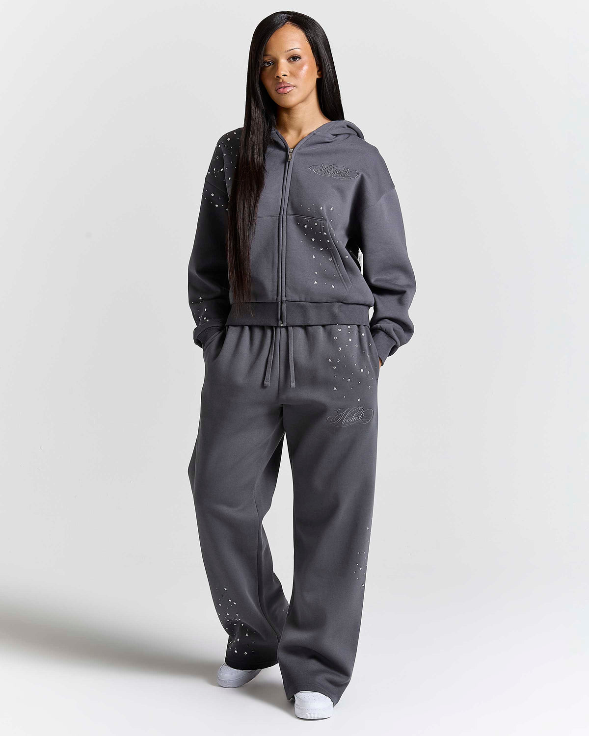Displays a model wearing the grey 'Hoodrich' branded women's Clash Full Tracksuit