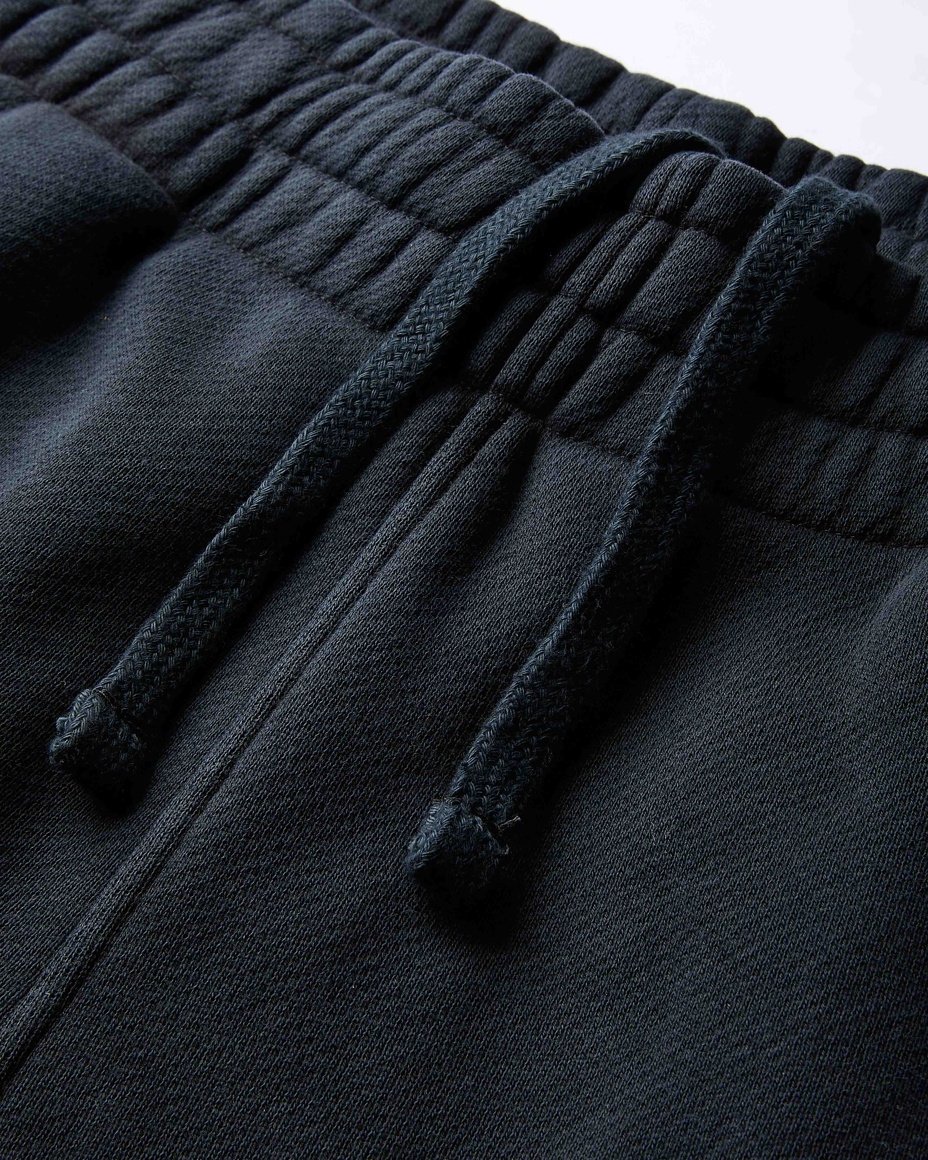 Dark gray fleece pants with drawstring on a light gray background