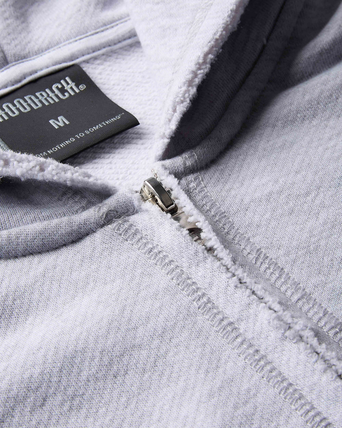 Close-up of a gray hoodie with a brand label on the zipper area.
