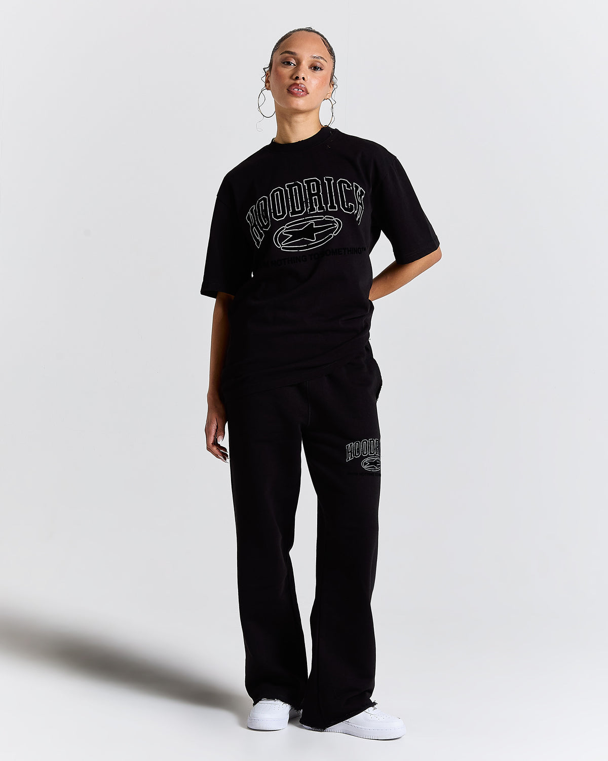 Person wearing a black 'Hoodrich' t-shirt and pants on a white background