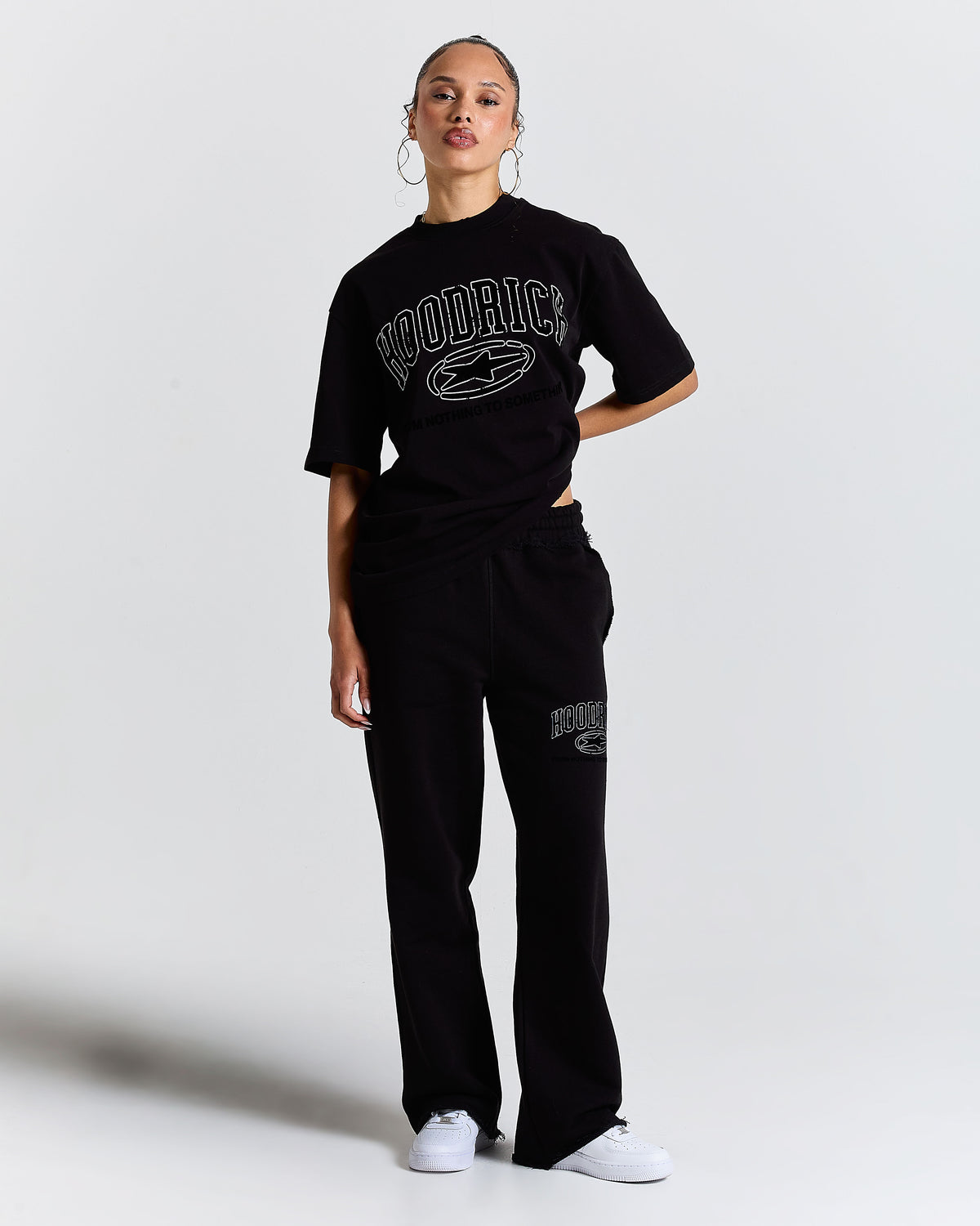 Person wearing a black 'Hoodrich' t-shirt and pants on a white background