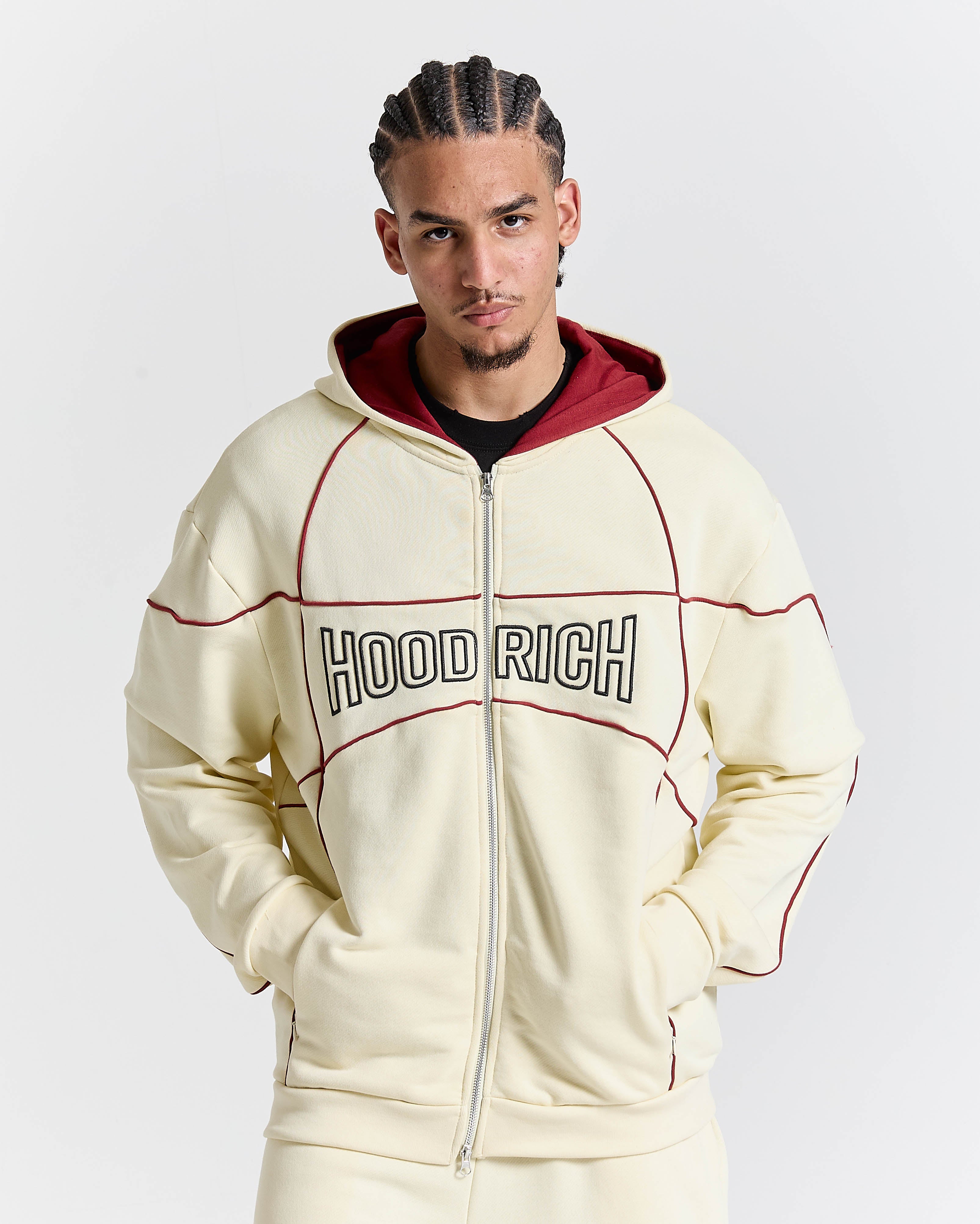 Man wearing a cream hoodie with 'HOOD RICH' text on a light gray background
