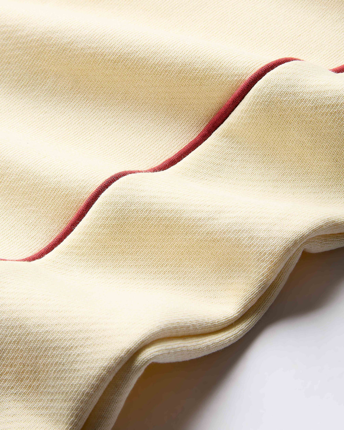 Close-up of beige fabric with red trim on a white background