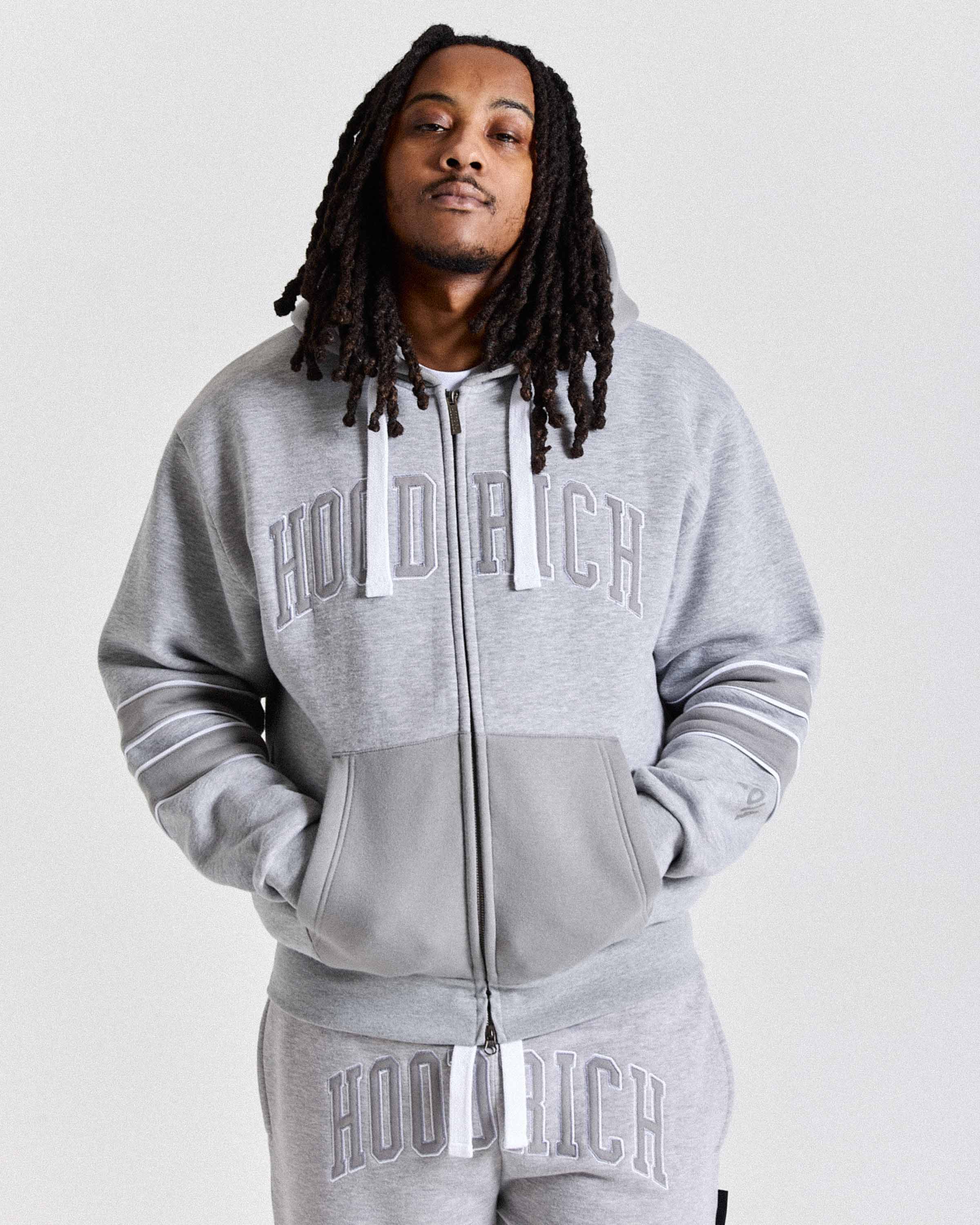 Person wearing a gray 'Hoodrich' tracksuit on a white background