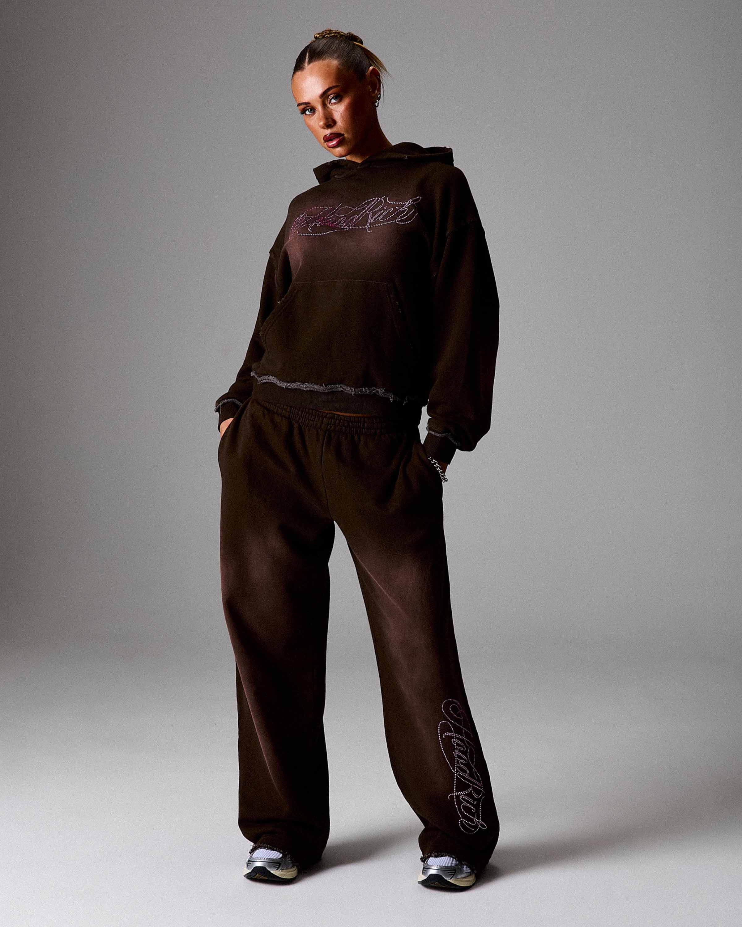 Person wearing a brown tracksuit with branding on a plain background