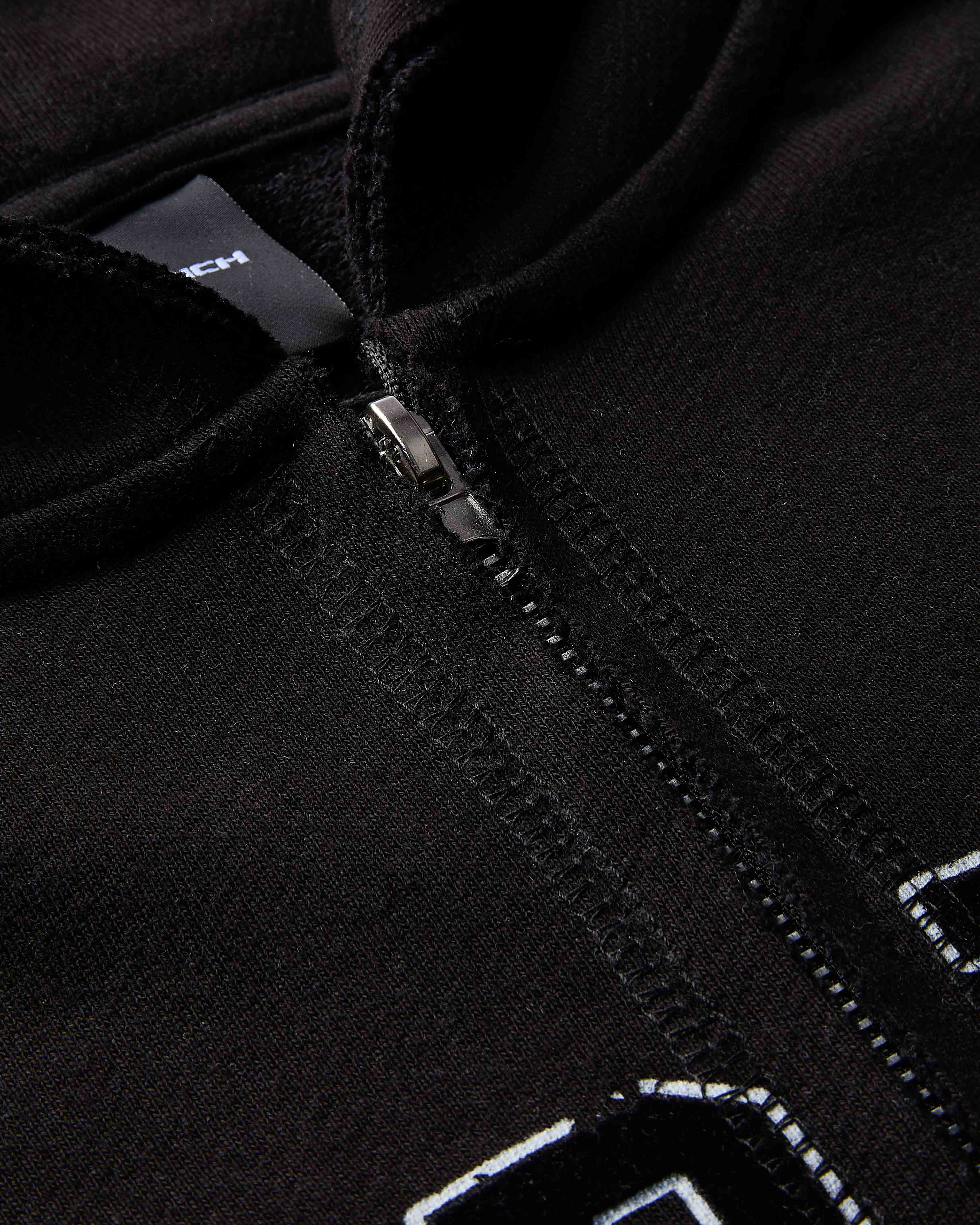 Close-up of a black jacket with a zipper and brand logo.