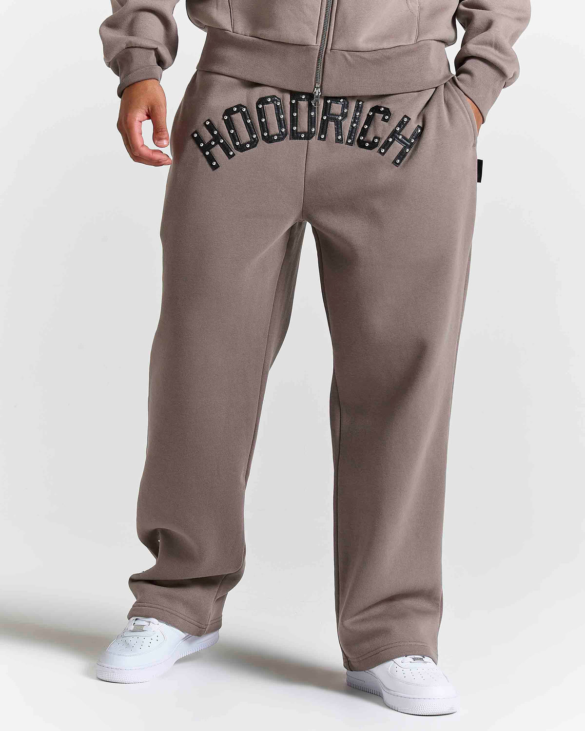 Displays a model wearing the Falcon Black 'Hoodrich' branded Varso Studs Oversized Wide Leg Jogger