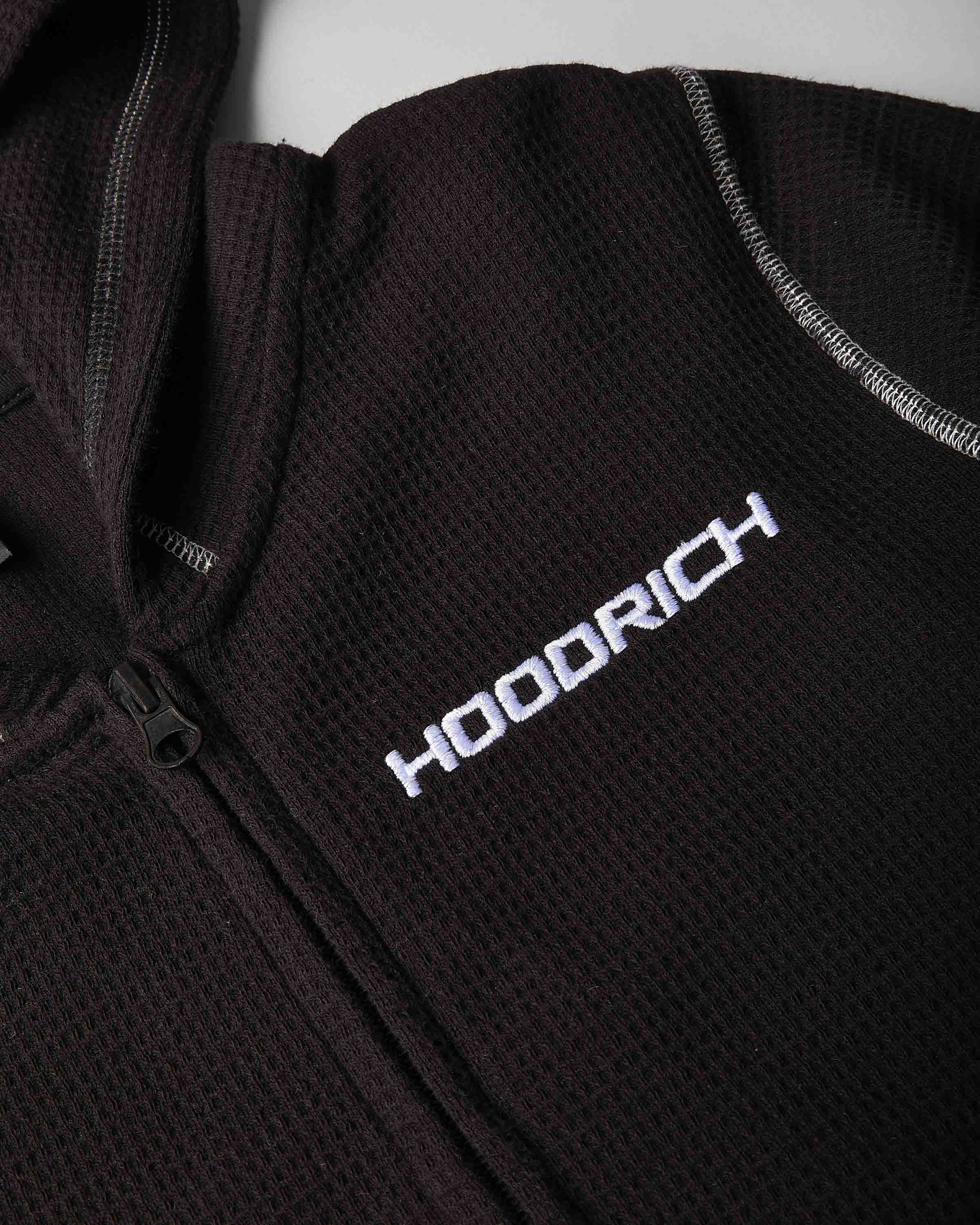 Close-up of a dark brown waffle-knit zip-up jacket with white embroidered 'HOODRICH' branding on the chest.