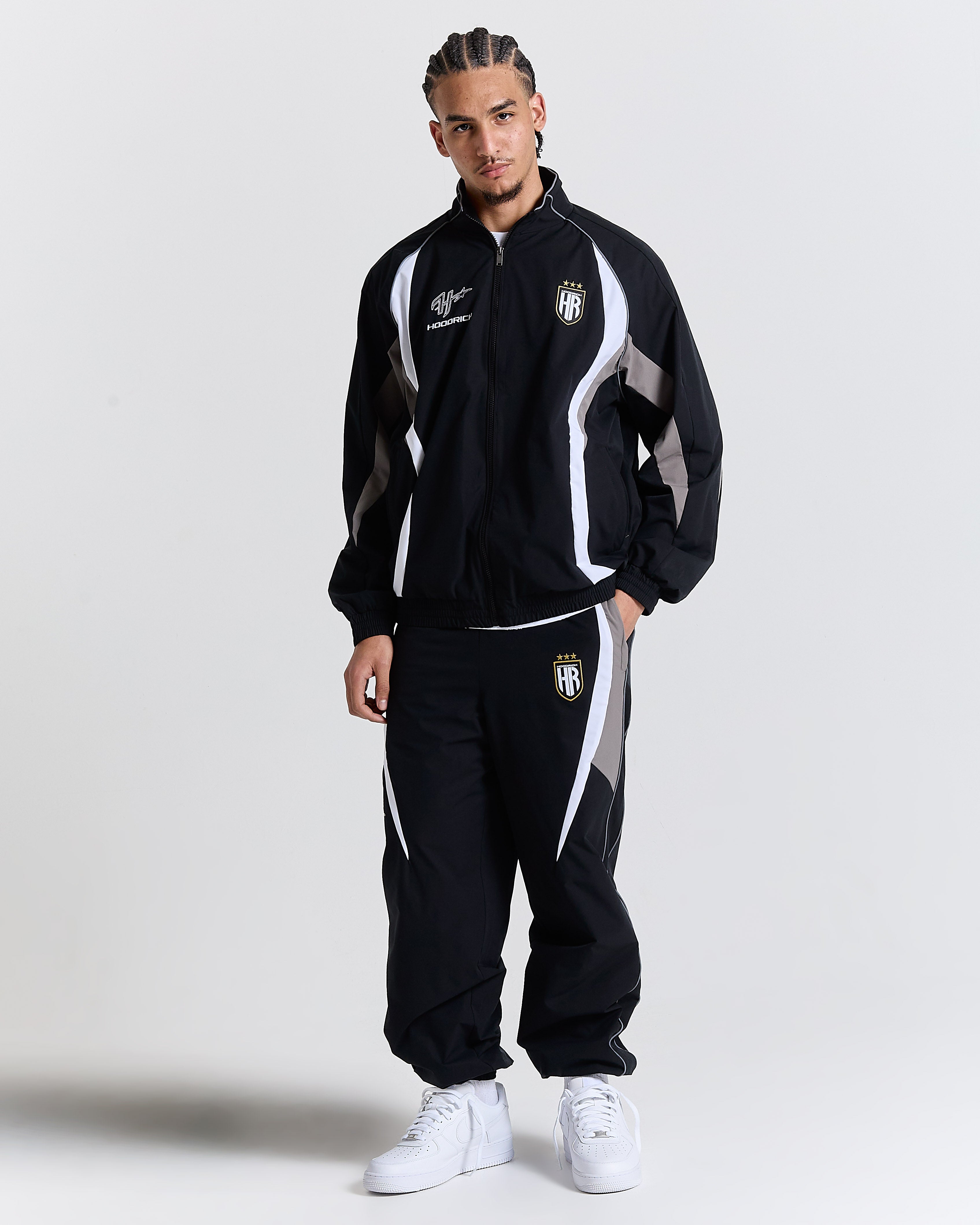 Male model wearing a black tracksuit with white accents on a light gray background