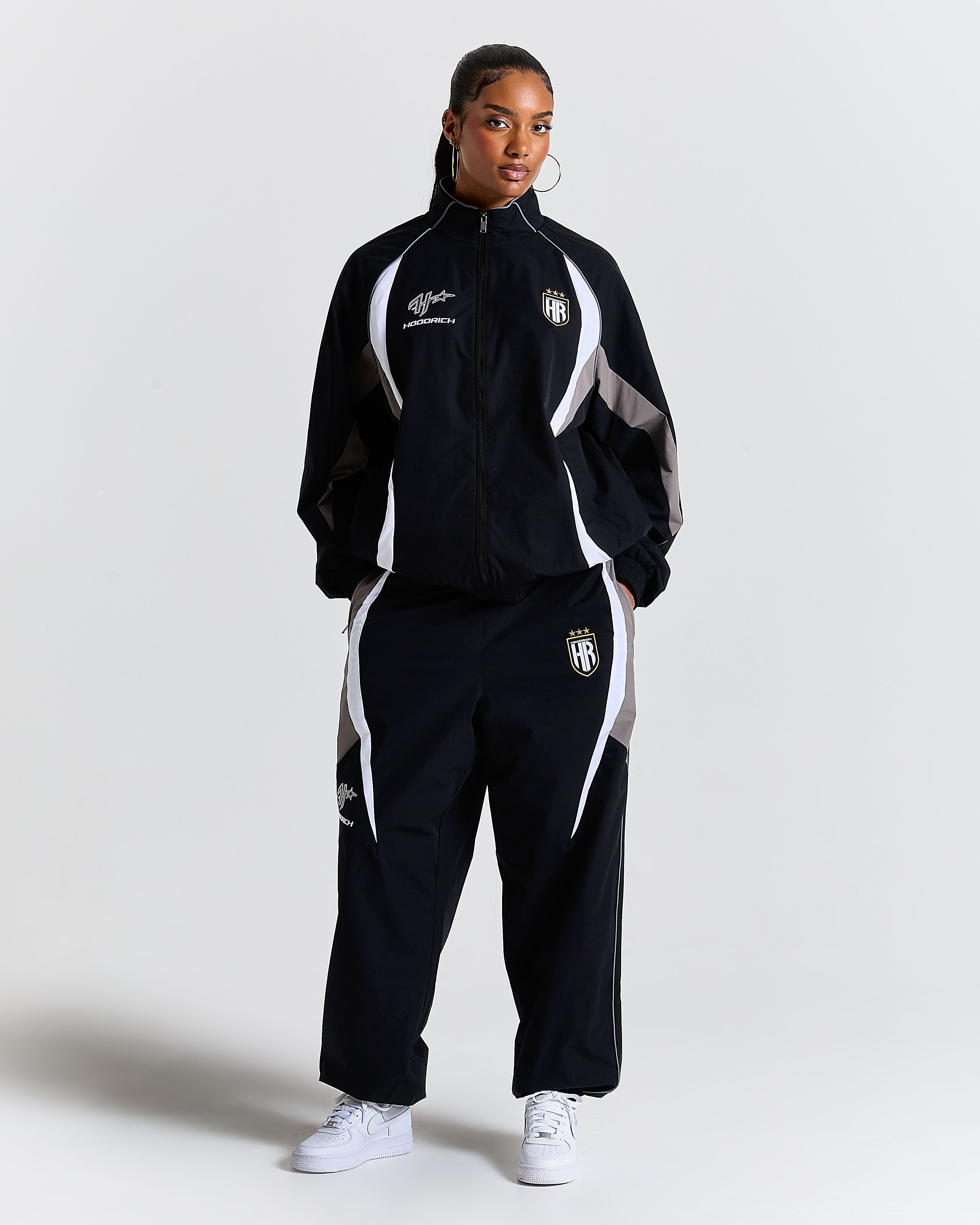 Person wearing a black tracksuit with white accents on a plain background