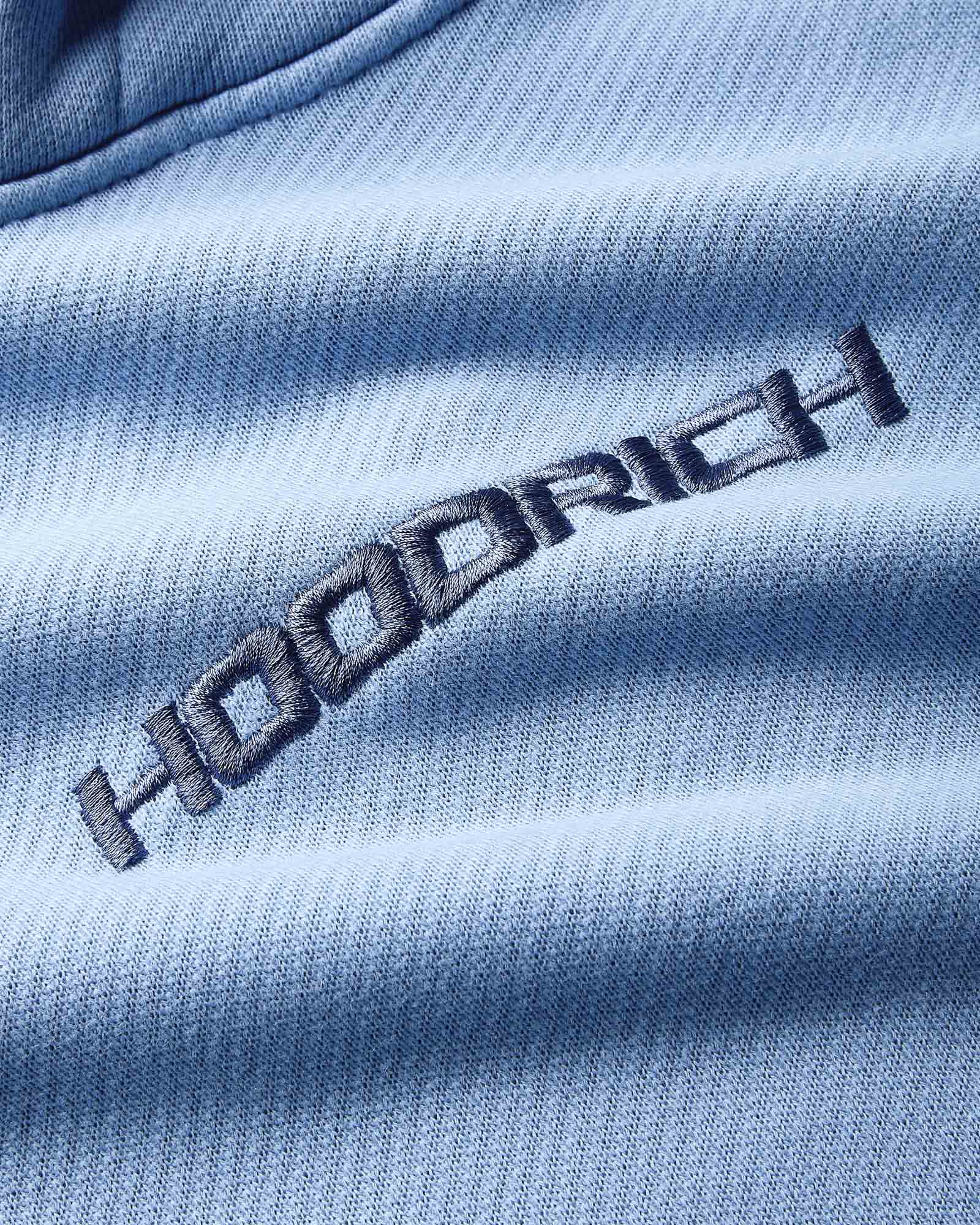 Close-up of a blue fabric with 'Hoodrich' embroidered on it
