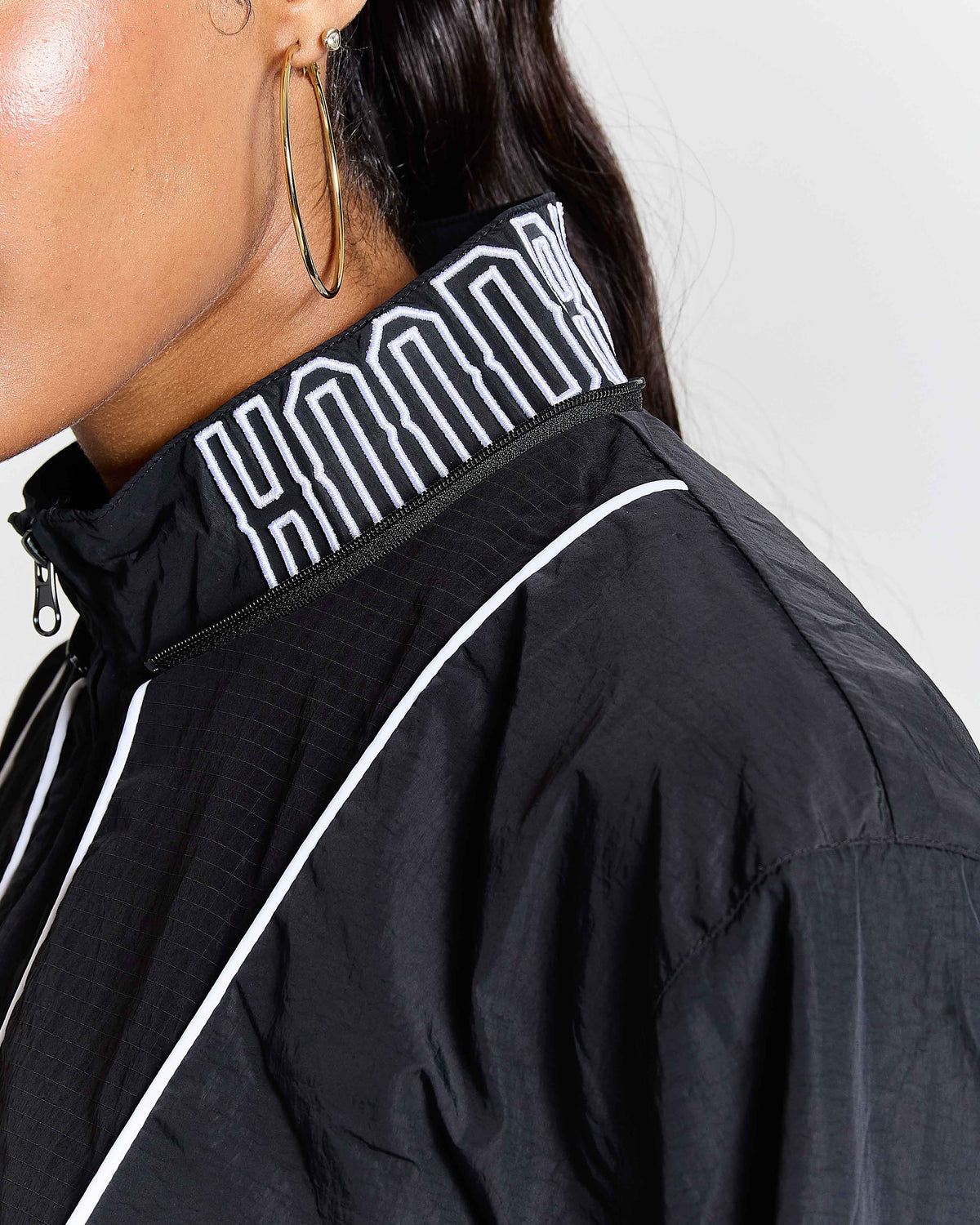 Black jacket with white piping and logo on a plain background