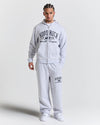 Man wearing a gray 'Hood Rich' tracksuit on a white background