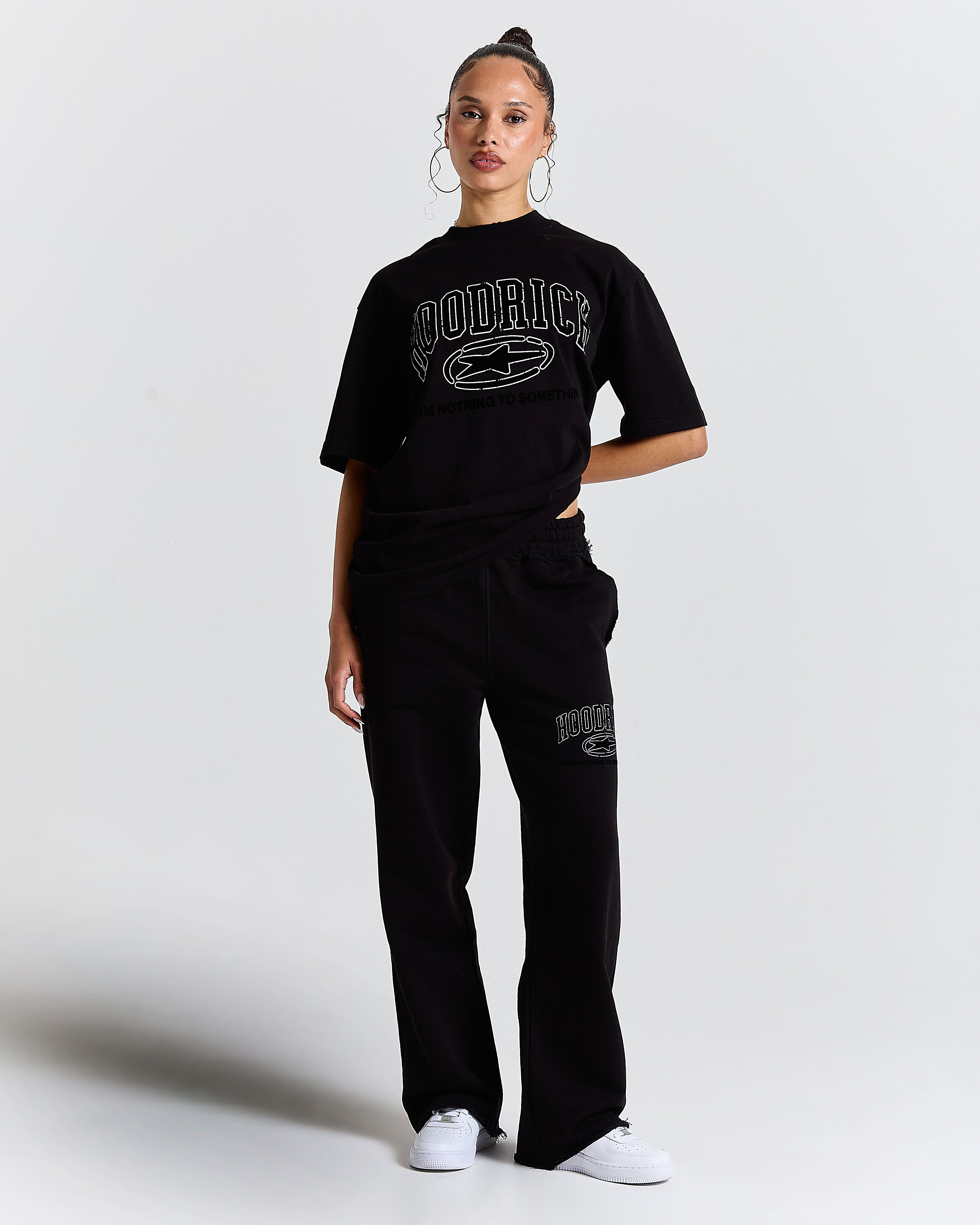 Person wearing a black 'Hoodrich' t-shirt and pants on a white background