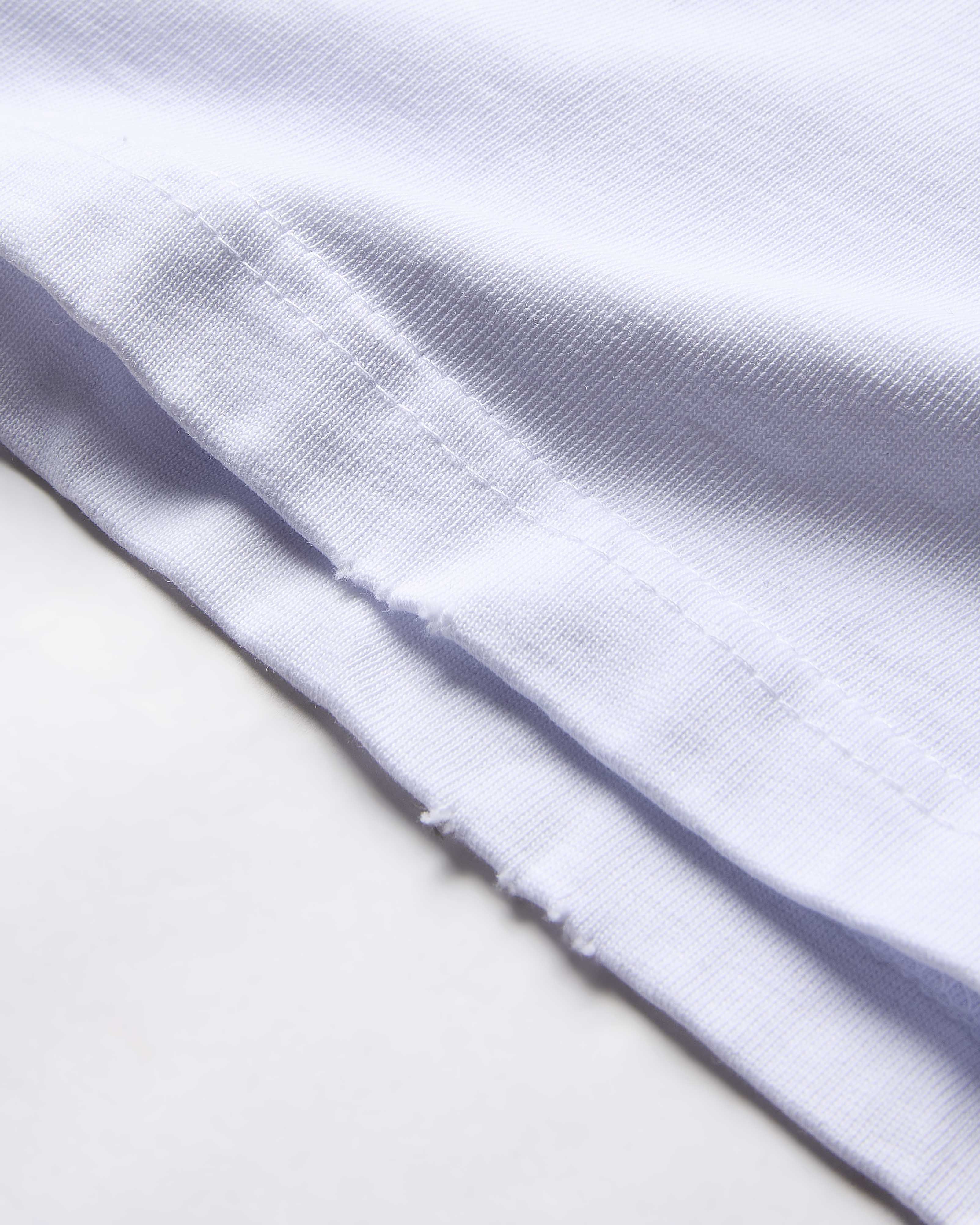 Extreme close-up of the textured white fabric on a Hoodrich t-shirt.