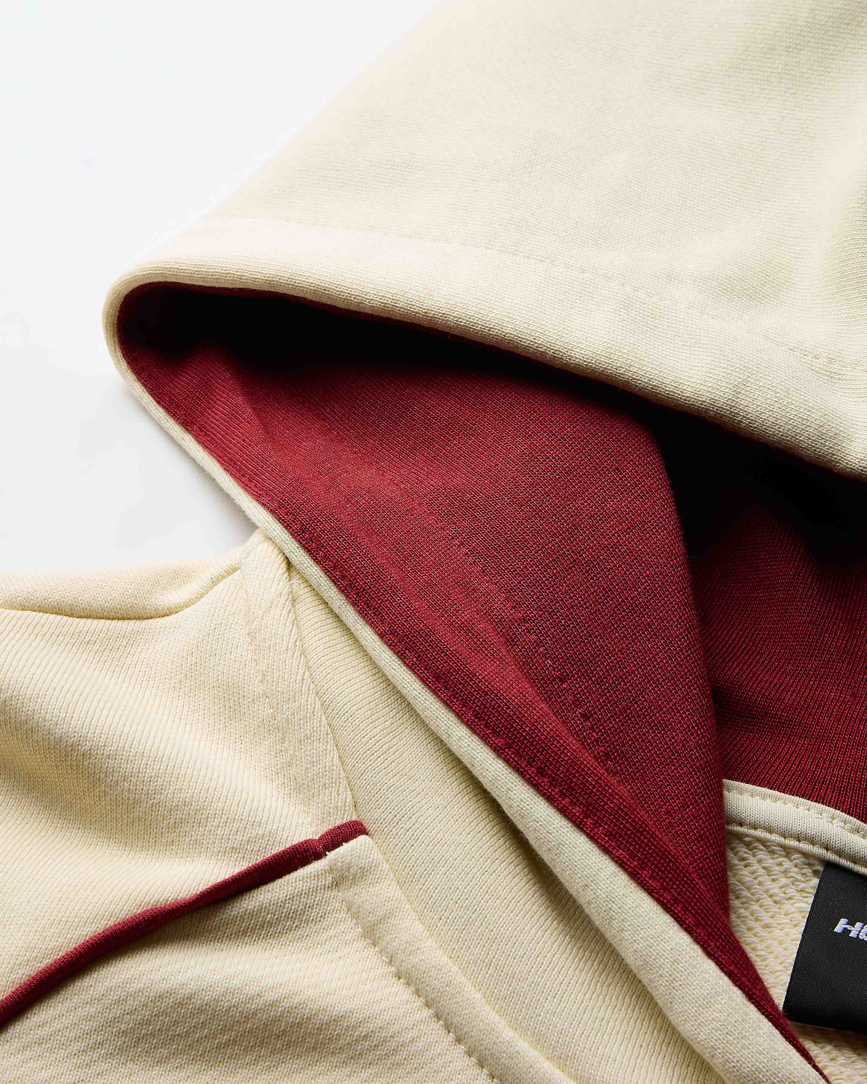 Close-up of a jacket with a red lining and beige exterior, featuring a brand label.