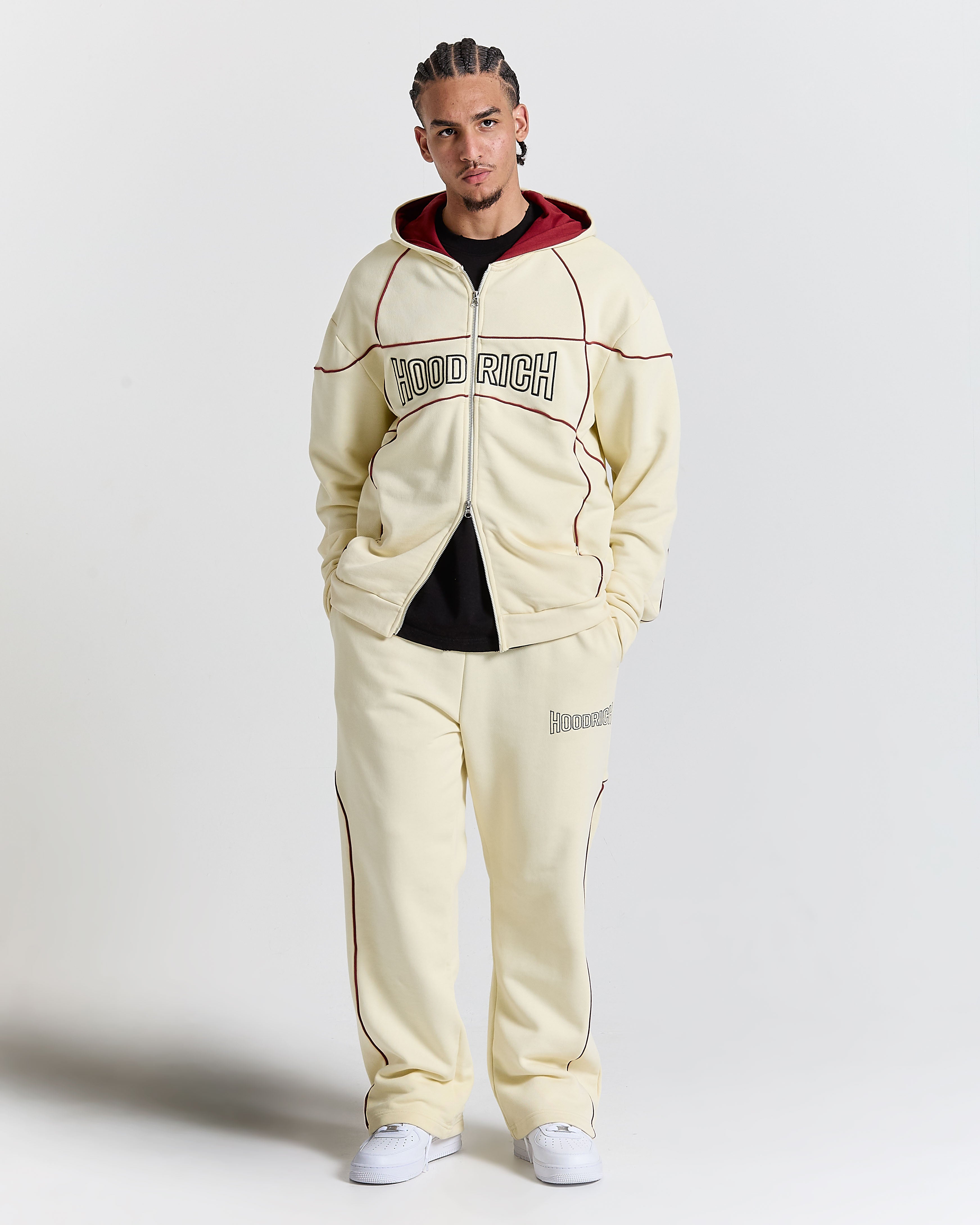 Person wearing a cream tracksuit with 'Hood Rich' branding on a white background