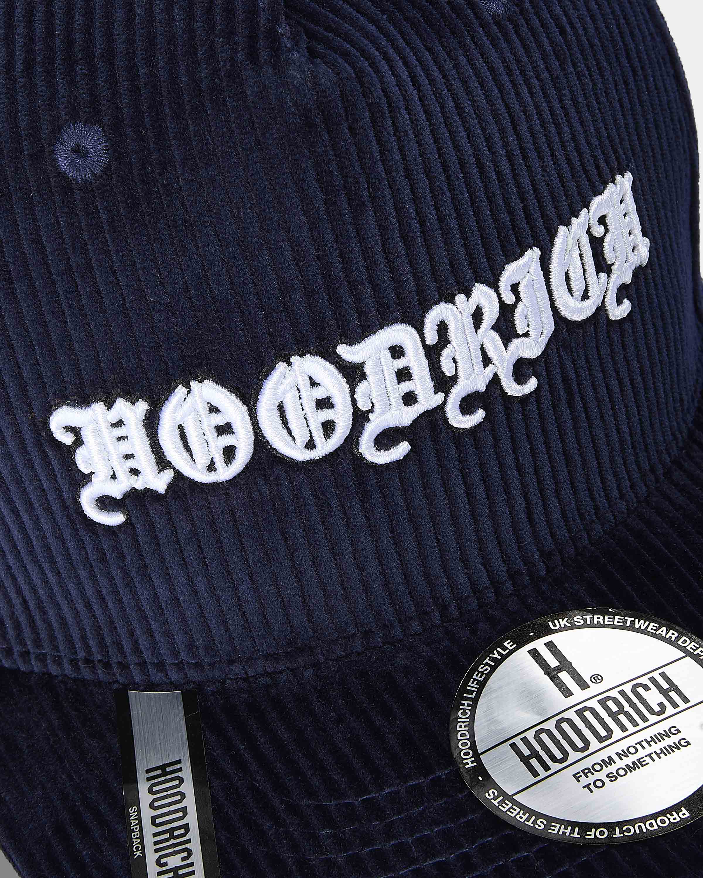 Navy blue cap with white embroidered text and Hoodrich logo on a dark background