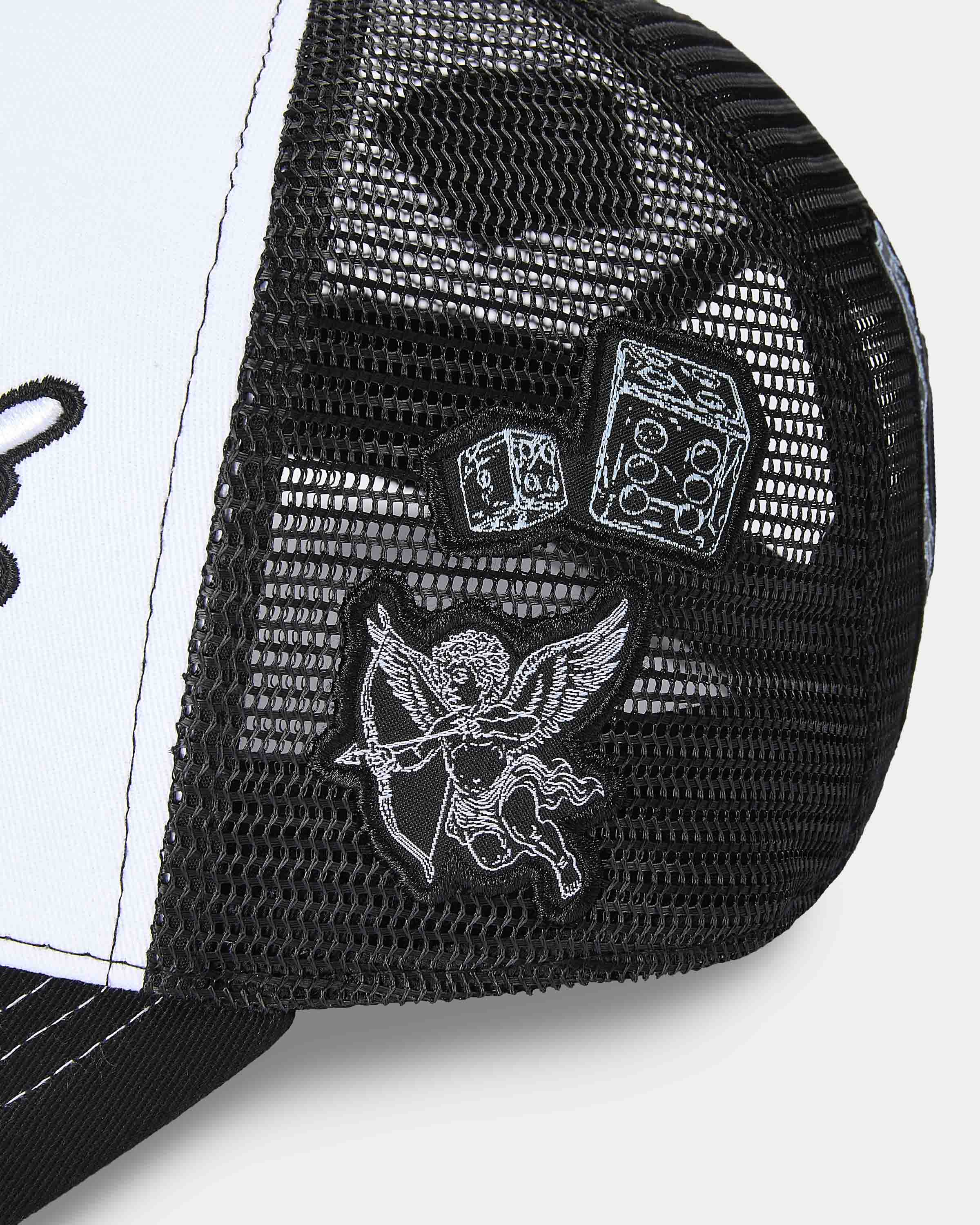 Close-up of a black and white cap with angel and devil designs on a white background