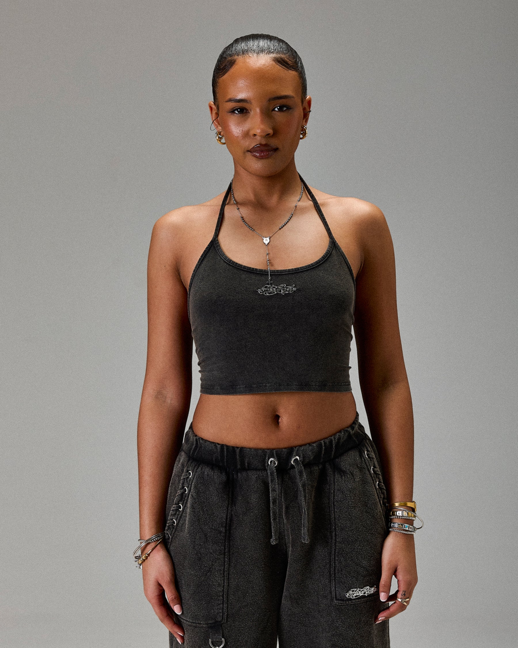 Person wearing a dark gray halter top and pants on a plain background