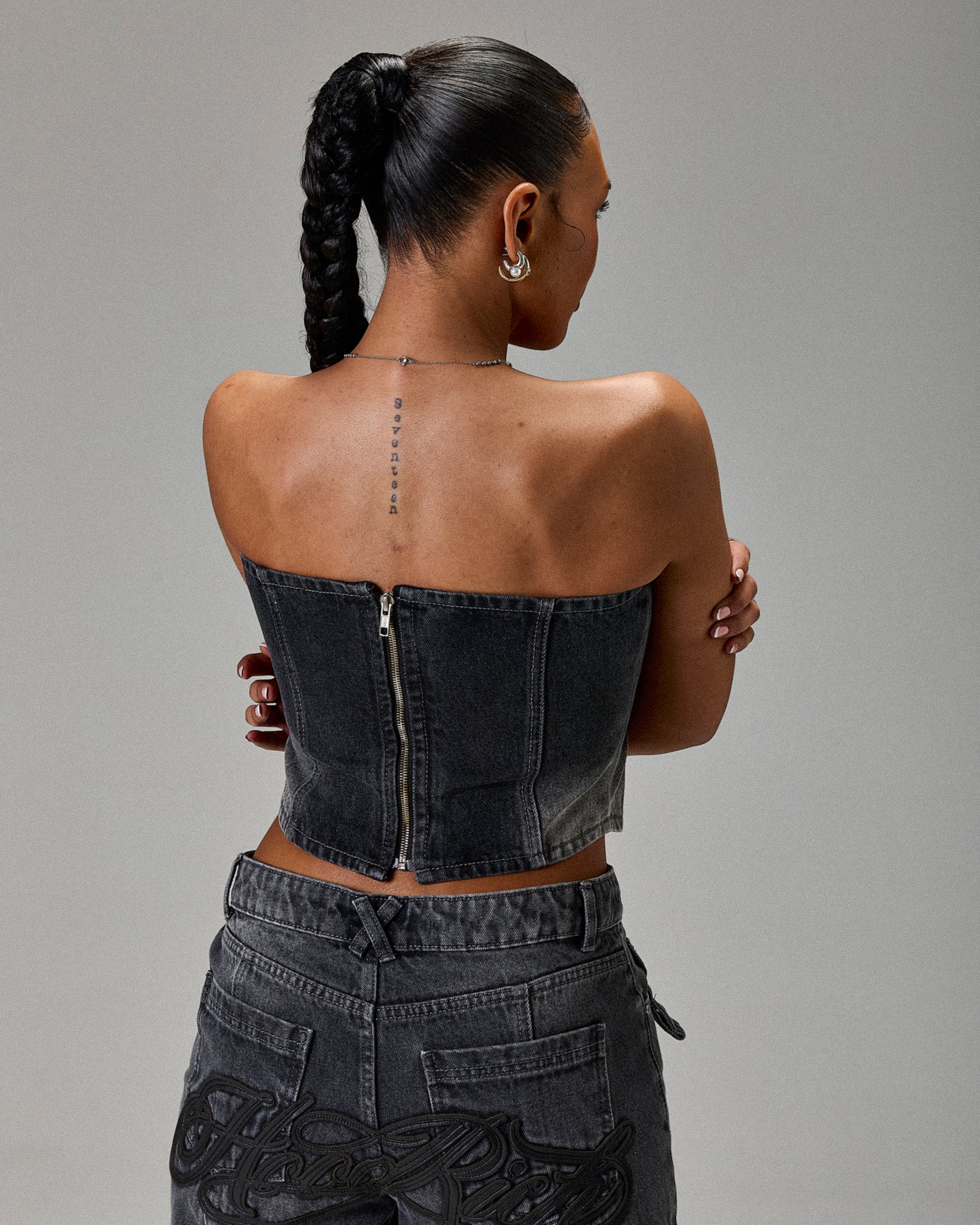 Person wearing a black strapless top and pants against a gray background