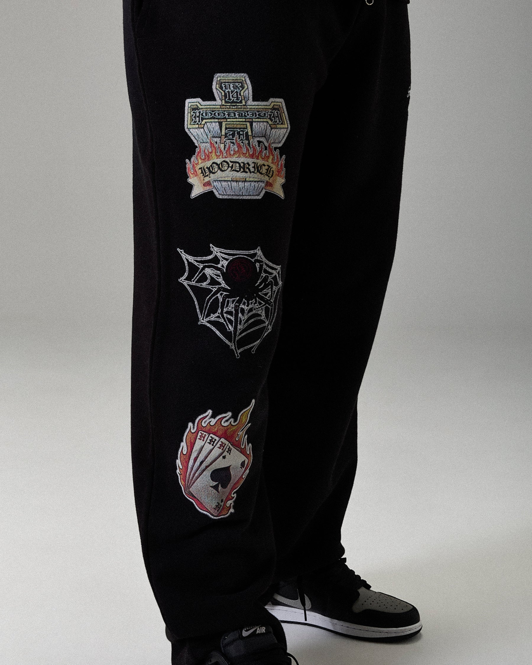Black pants with embroidered patches on a gray background