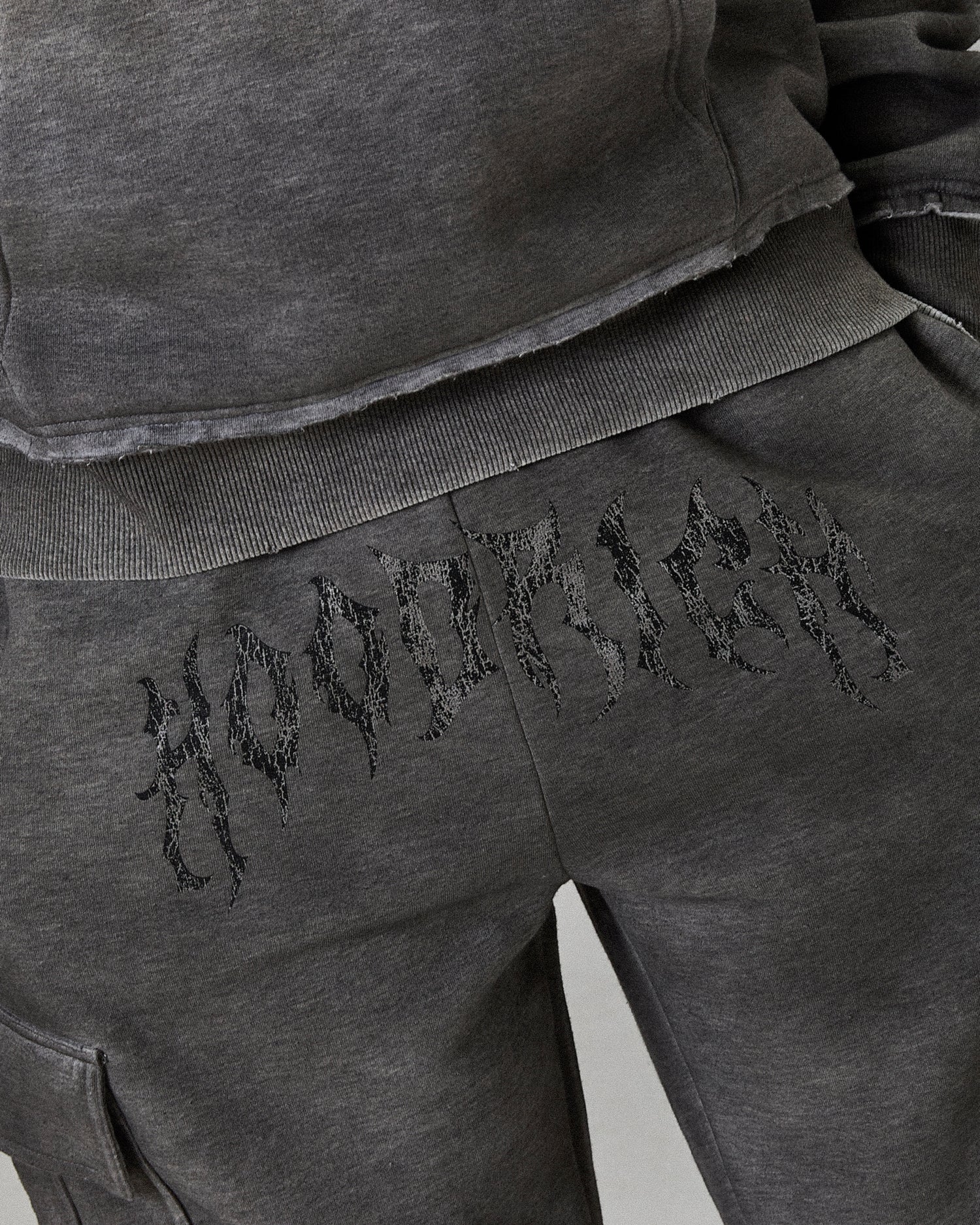 Gray sweatpants with embroidered text on a plain background