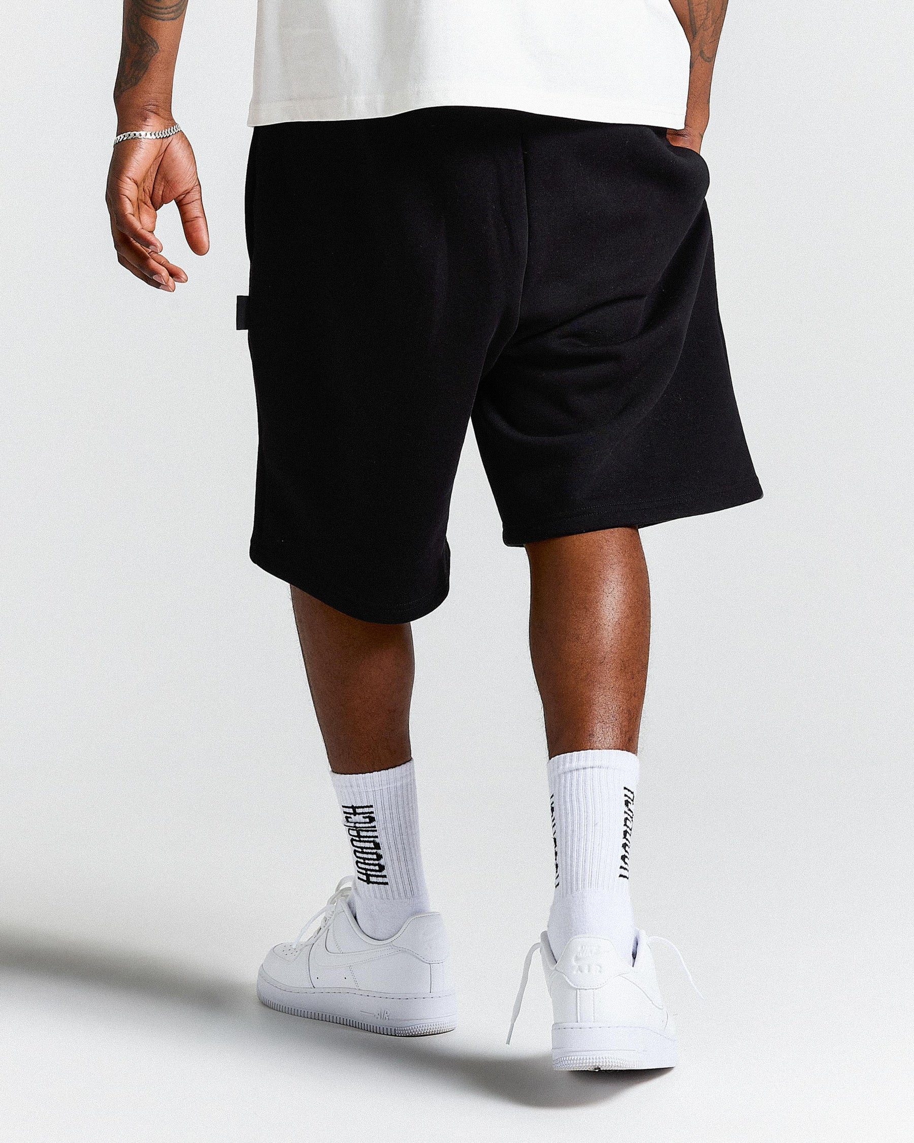 Person wearing black shorts and white sneakers on a plain background