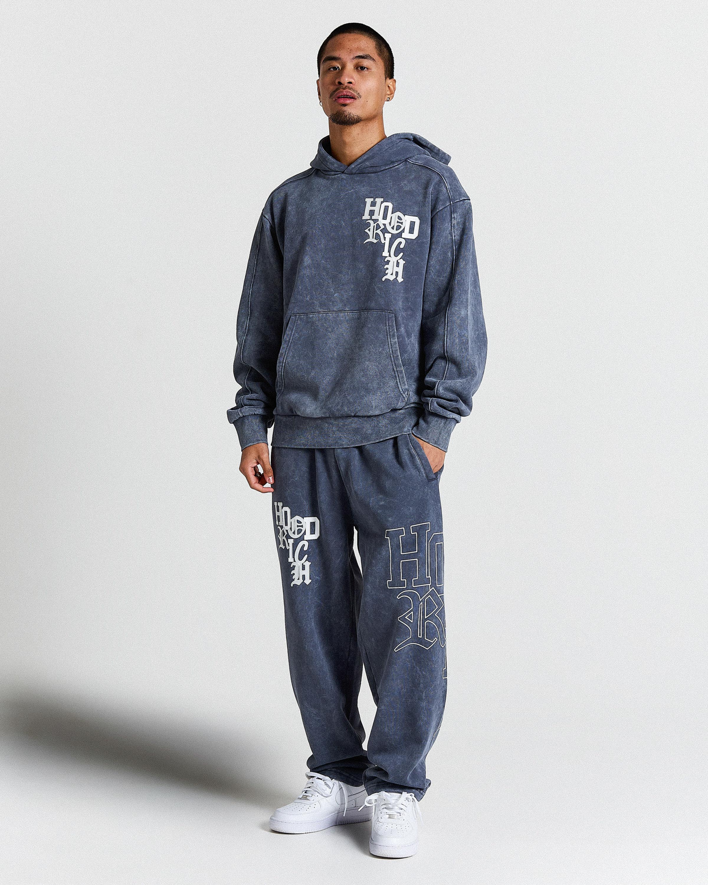 Displays a model wearing the Blue & white 'Hoodrich' branded Heritage Full Tracksuit 