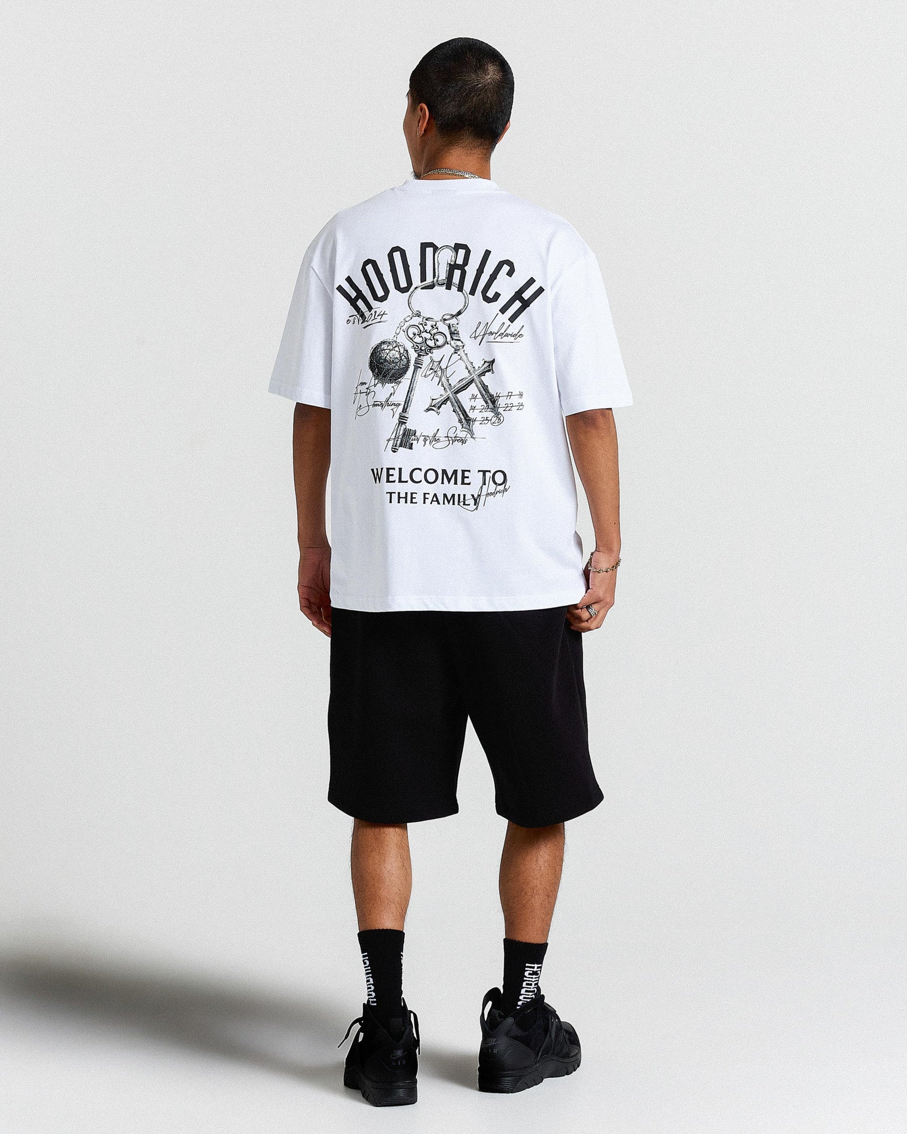 Person wearing a white t-shirt with text and graphics, standing against a plain background