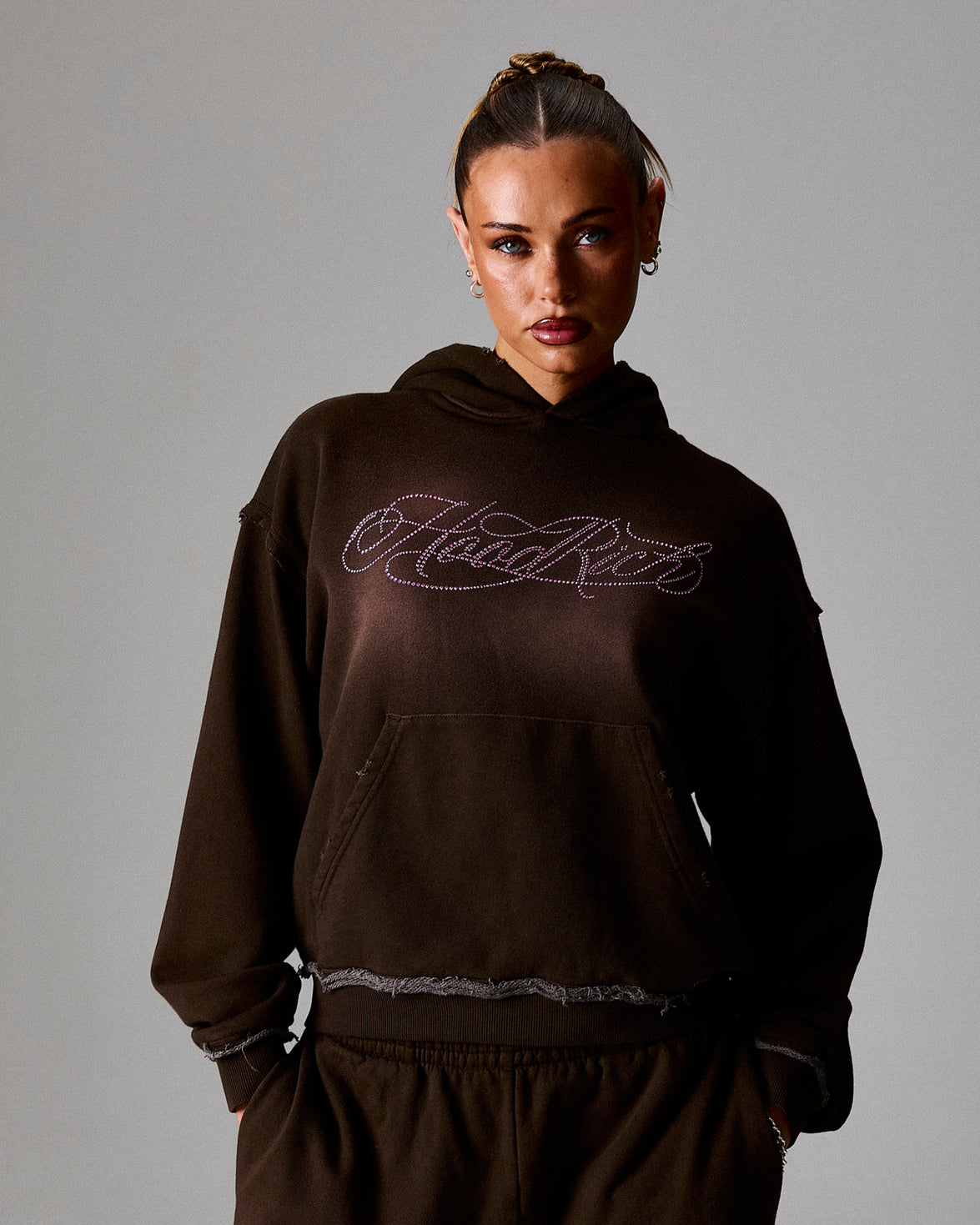 Person wearing a dark brown hoodie with 'Hoodrich' text on a gray background