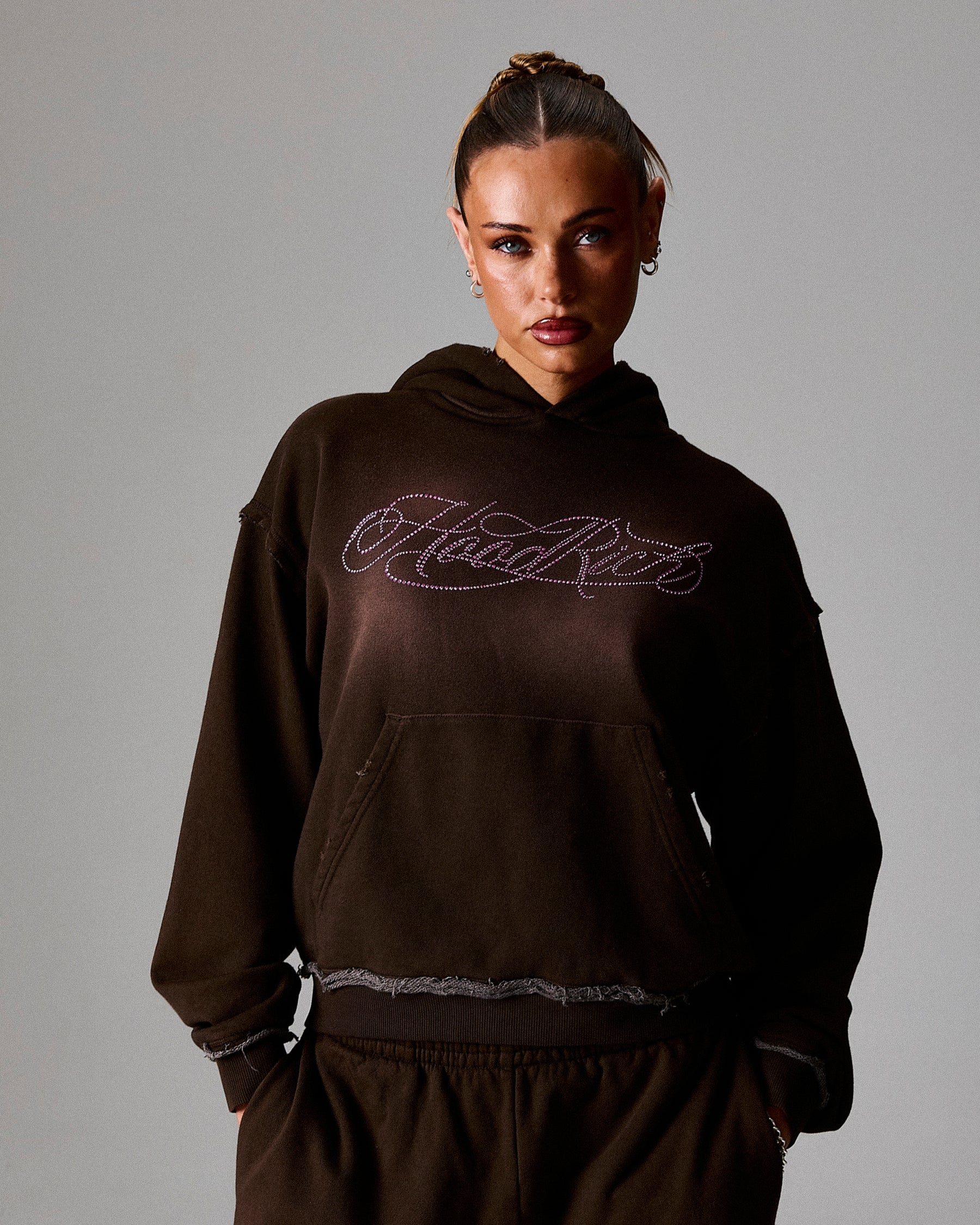 Person wearing a dark brown hoodie with 'Hoodrich' text on a gray background