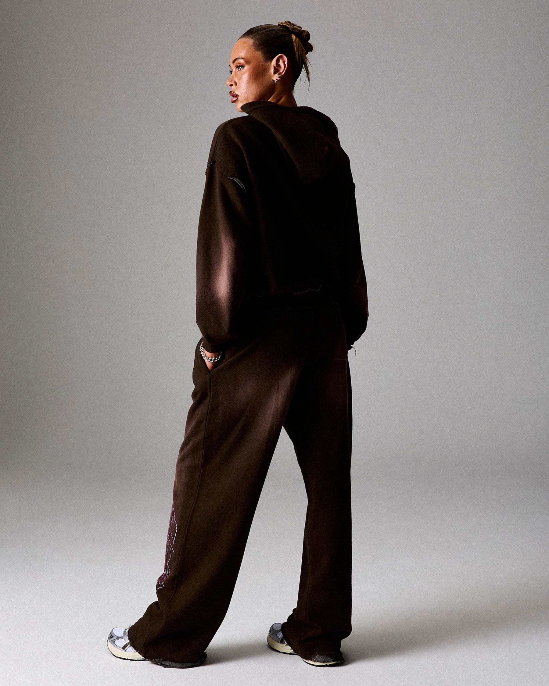 Person wearing a dark brown tracksuit standing against a plain background