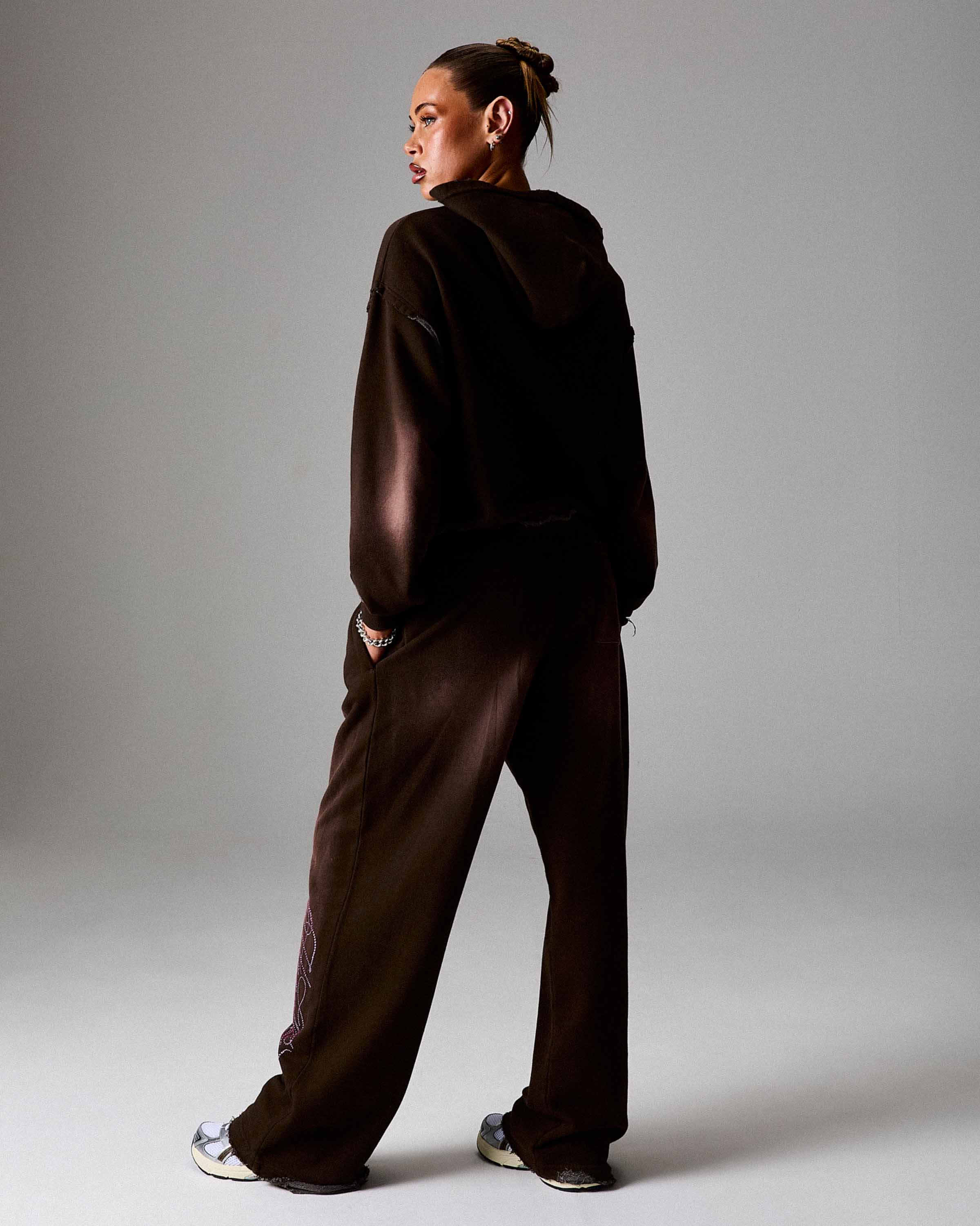 Person wearing a dark brown tracksuit against a plain background
