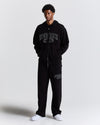Person wearing a black 'Hood Rich' tracksuit on a white background