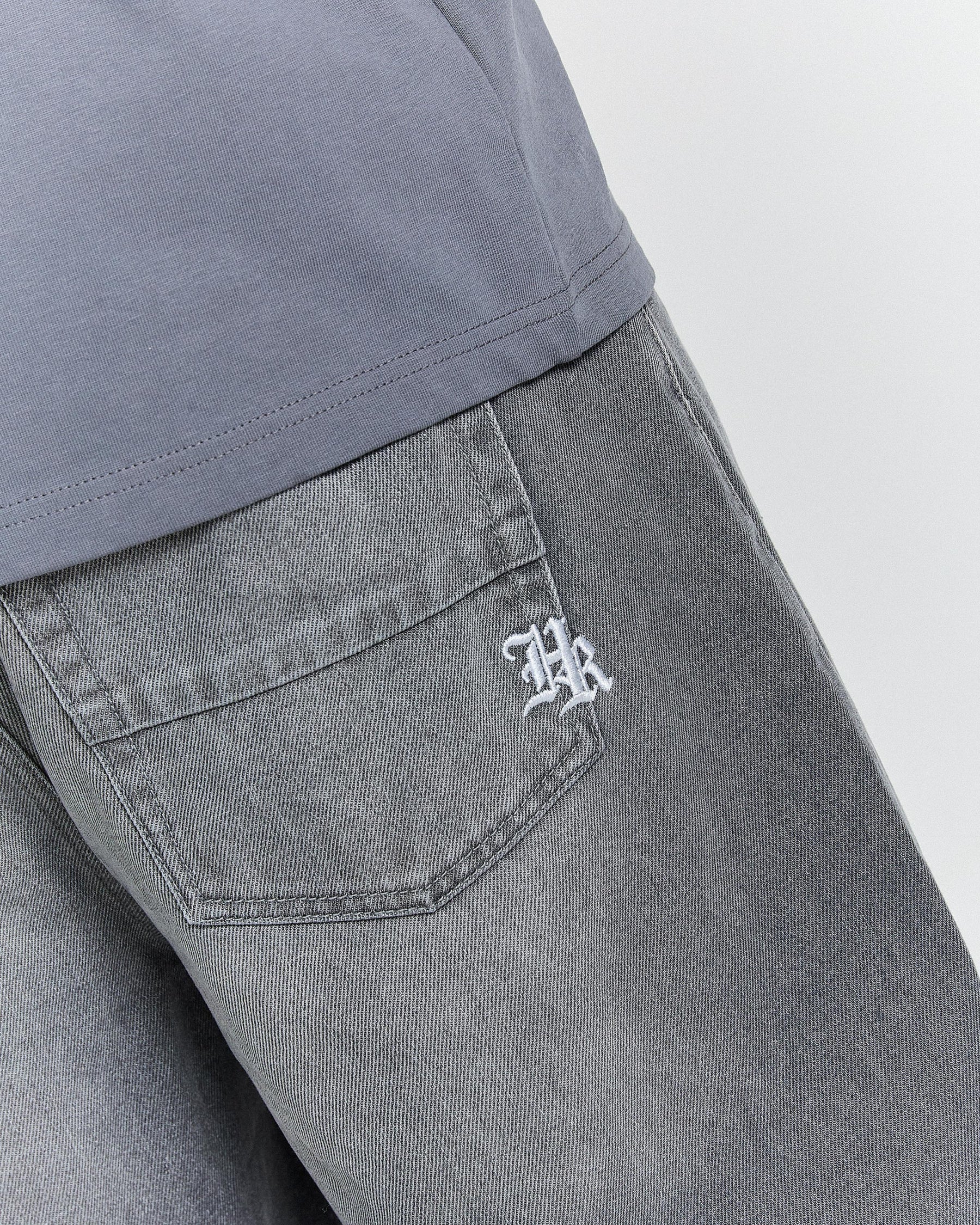 Gray pants with a logo on the pocket against a light gray background