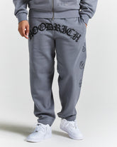 Person wearing gray sweatpants with branding on a white background