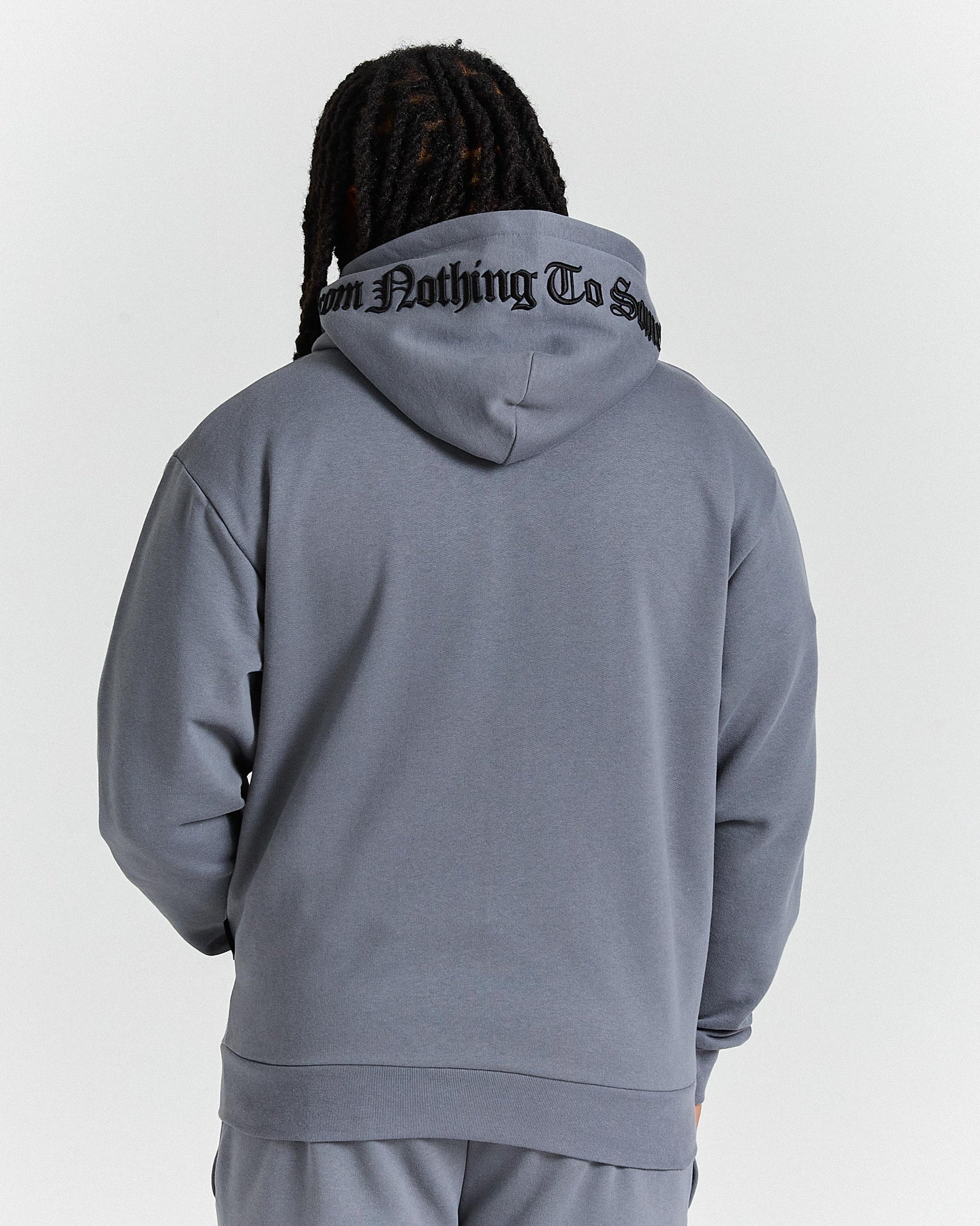 Person wearing a gray hoodie with text on the back against a white background