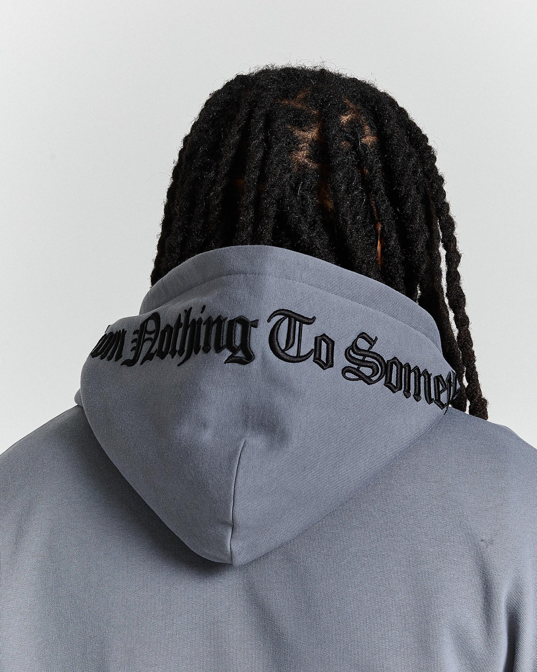 Person wearing a gray hoodie with text on the hood, facing away from the camera.