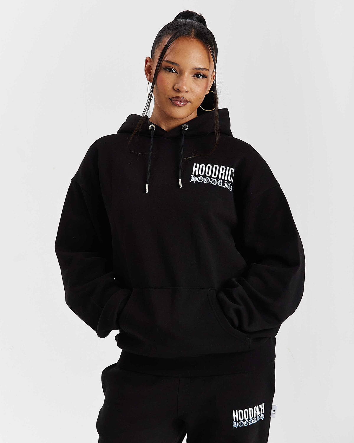 Displays a model wearing the Black 'Hoodrich' branded women's Flex Full Tracksuit 